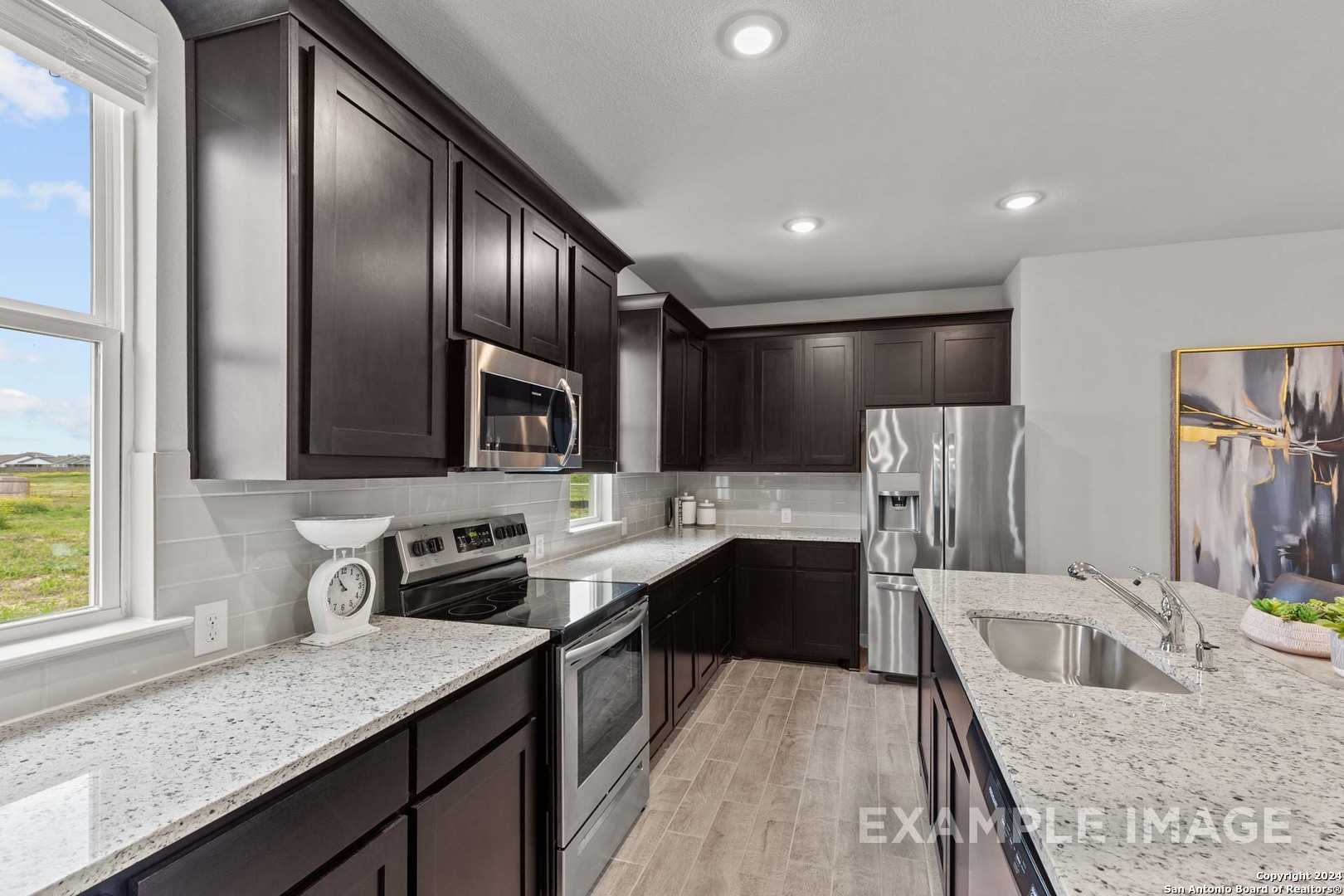Modern kitchen with dark cabinets, granite counters, stainless appliances in 3-bed Davidson Homes Collin A, Seguin, TX