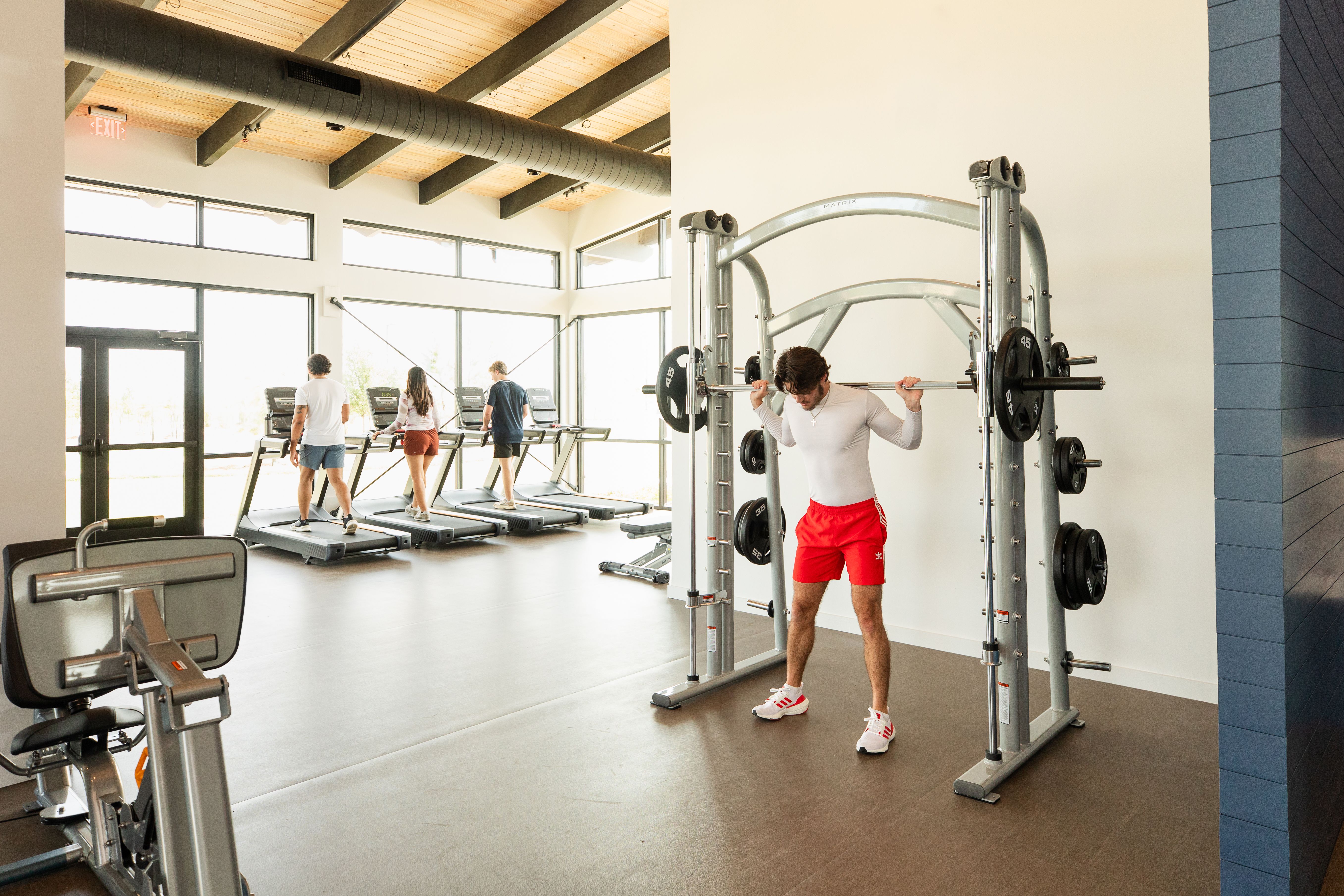 Spacious fitness center at Emberly in Beasley Texas with squat rack workout treadmills and large windows