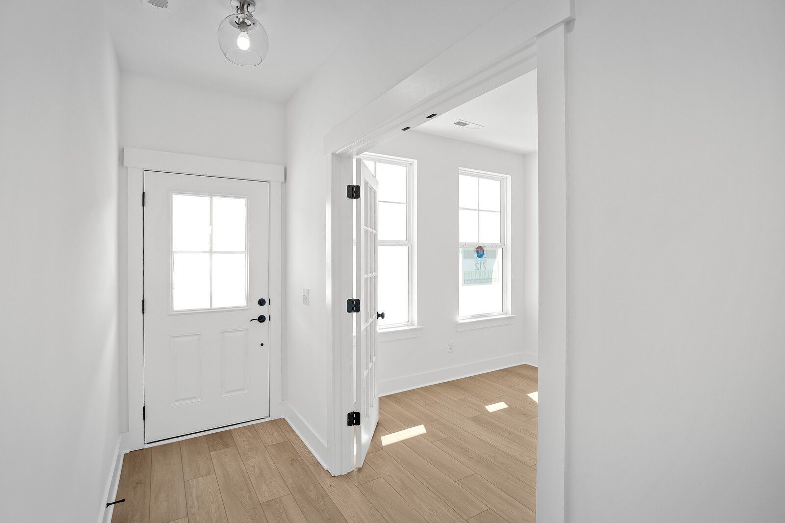 Bright foyer with white paneled doors, oak hardwood floors, and sunlit windows in Davidson Homes The Logan C, Gallatin, TN