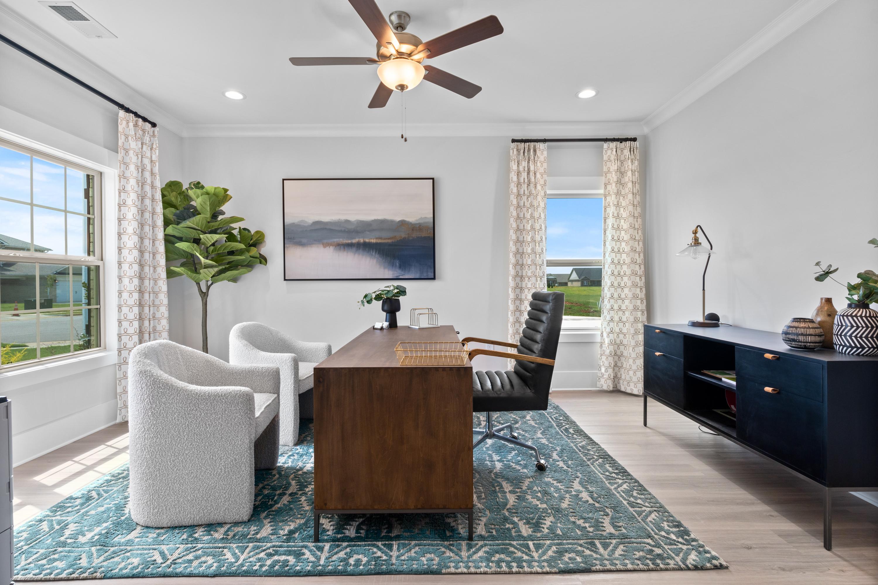Stylish home office in The Chelsea A with wooden desk, leather chair, white armchairs, abstract art, and large windows