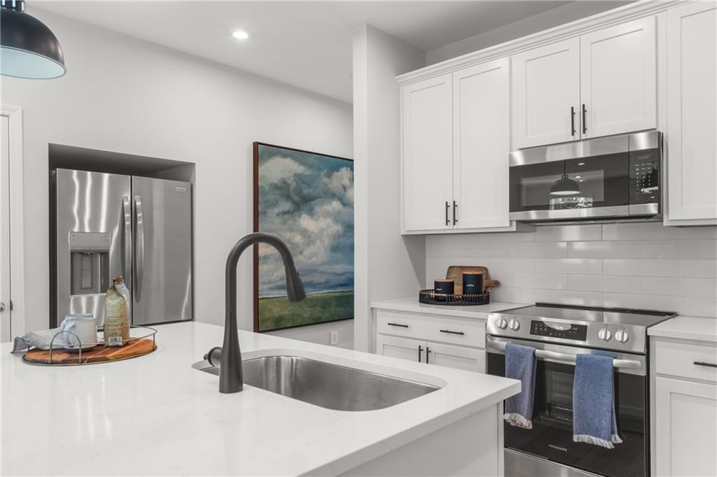 Modern white kitchen with stainless steel appliances, quartz countertops, subway tile backsplash in Davidson Homes The Durant A, Emerson, GA