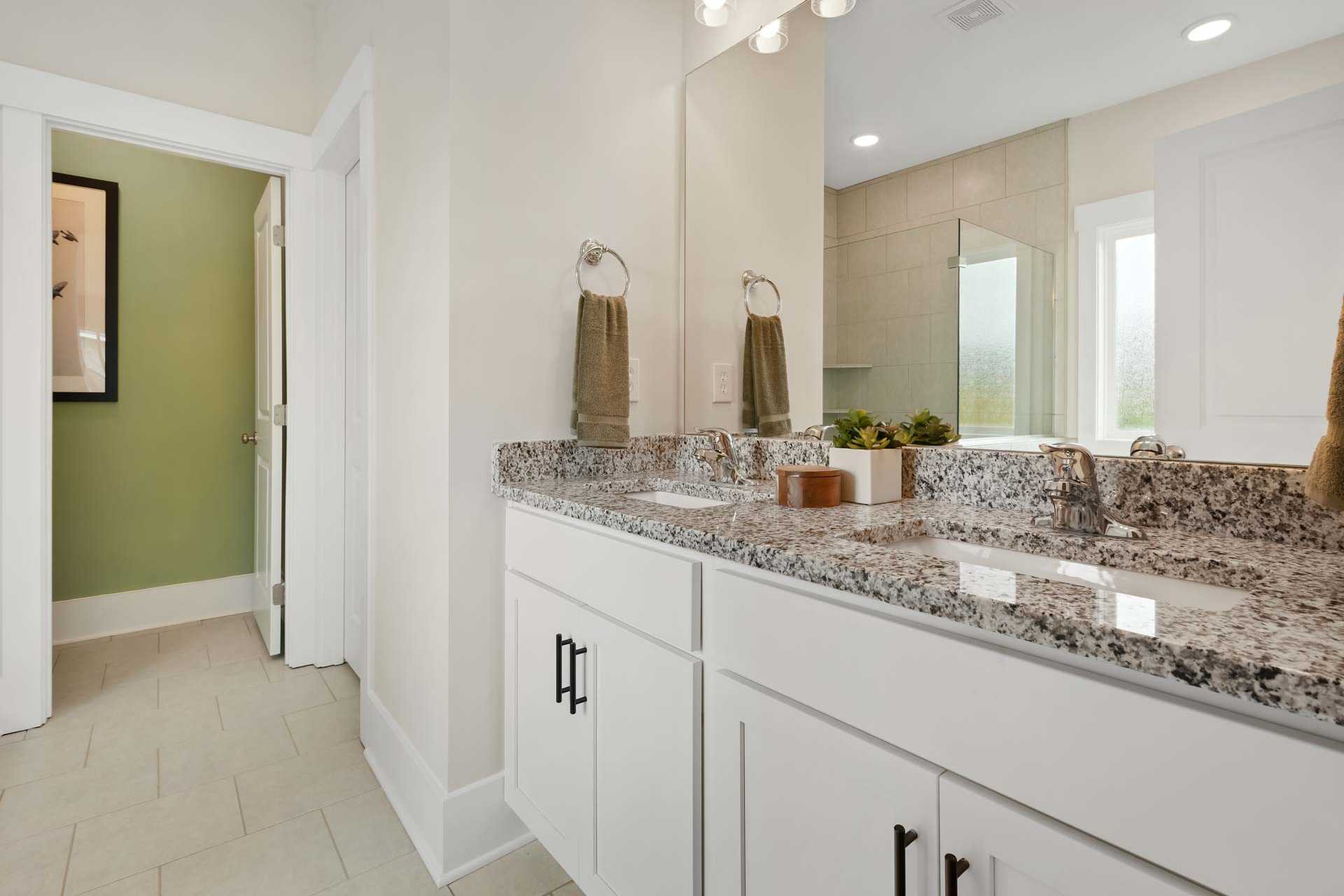 Spacious master bathroom at Durham Farms in Harvest Alabama featuring double granite vanity white cabinets mirrors and glass shower