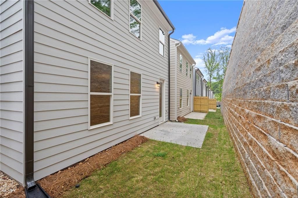Two-story Cary A home exterior with white clapboard siding, large windows, side entry, and fenced grassy yard in The Village at Shallowford, Kennesaw, Georgia