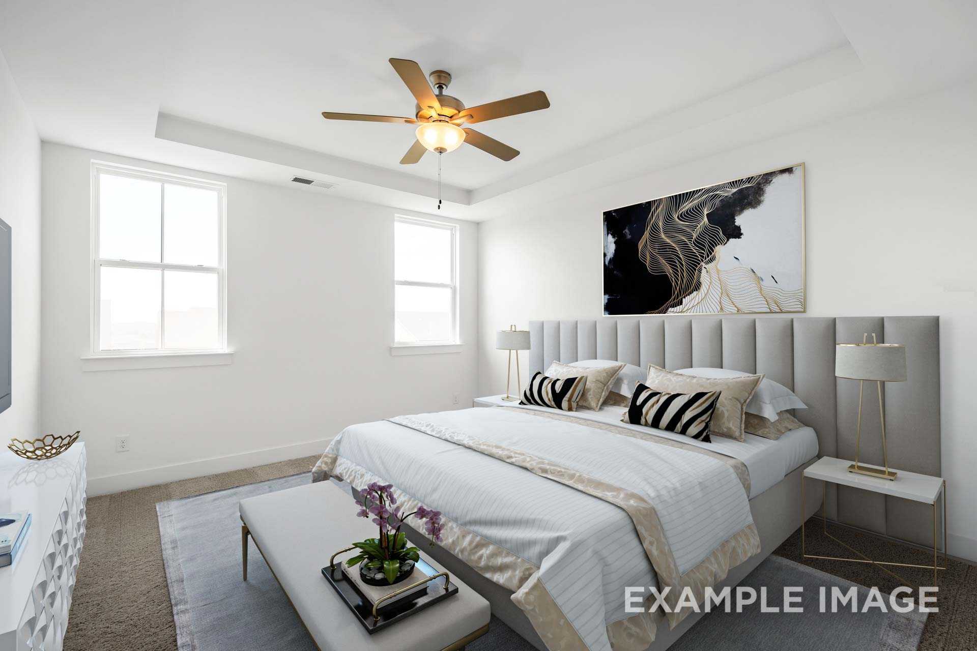 Spacious master bedroom in The Ash home with king bed, zebra pillows, gold accents, and abstract art wall