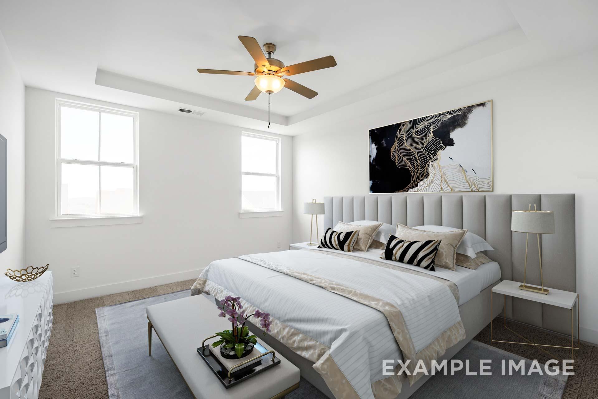 Spacious master bedroom in The Ash home with king bed, zebra pillows, gold accents, and abstract art wall