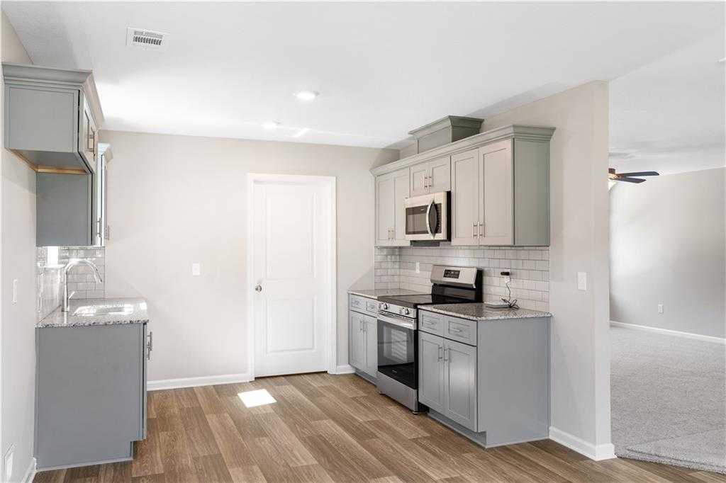 Modern gray shaker cabinet kitchen with stainless steel appliances, white subway tile backsplash, and hardwood floors in Davidson Homes The Washington, Phenix City