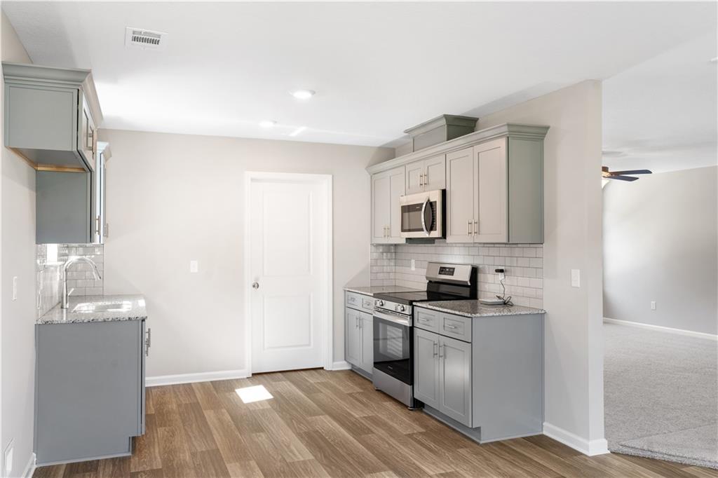 Modern gray shaker cabinet kitchen with stainless steel appliances, white subway tile backsplash, and hardwood floors in Davidson Homes The Washington, Phenix City