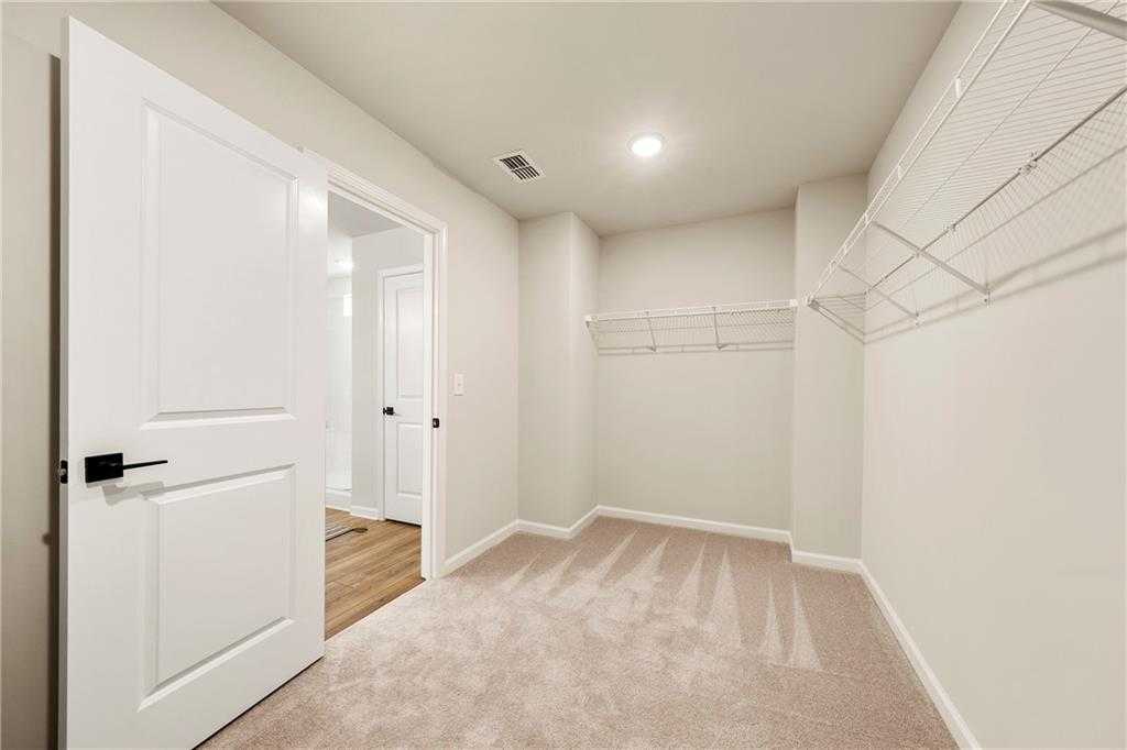 Spacious walk-in closet with wire shelving, carpeted floor, and open doors in Davidson Homes The Hickory B, Riverwood, Dallas, Georgia