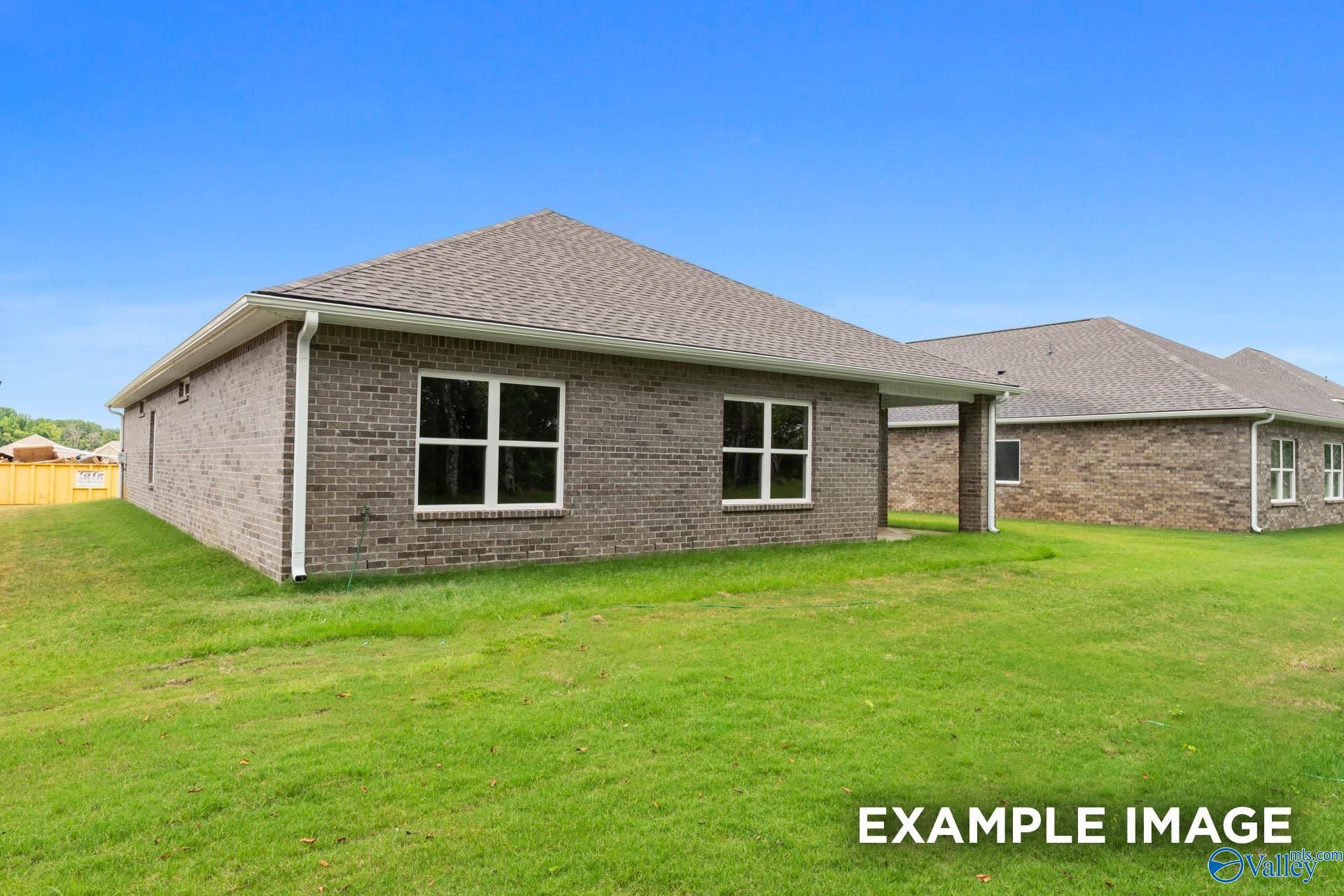 Single-story brick home exterior with 2-car garage, covered entry, and green lawn in Carroll Green, Harvest, Alabama by Evermore Homes The Daphne E