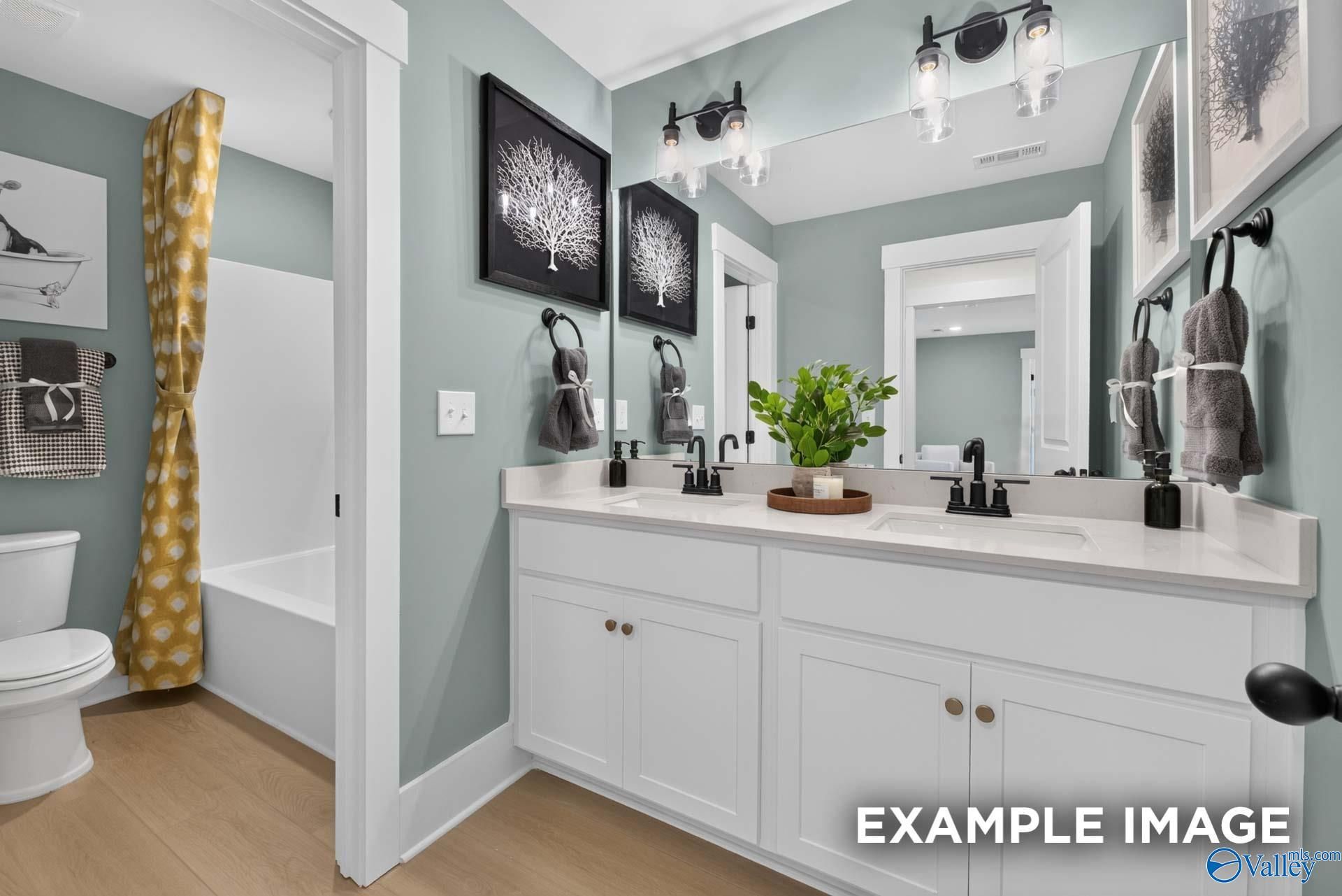Dual vanity bathroom with white cabinets, black fixtures, and sage green walls in Davidson Homes Ashport K, Hazel Green, AL
