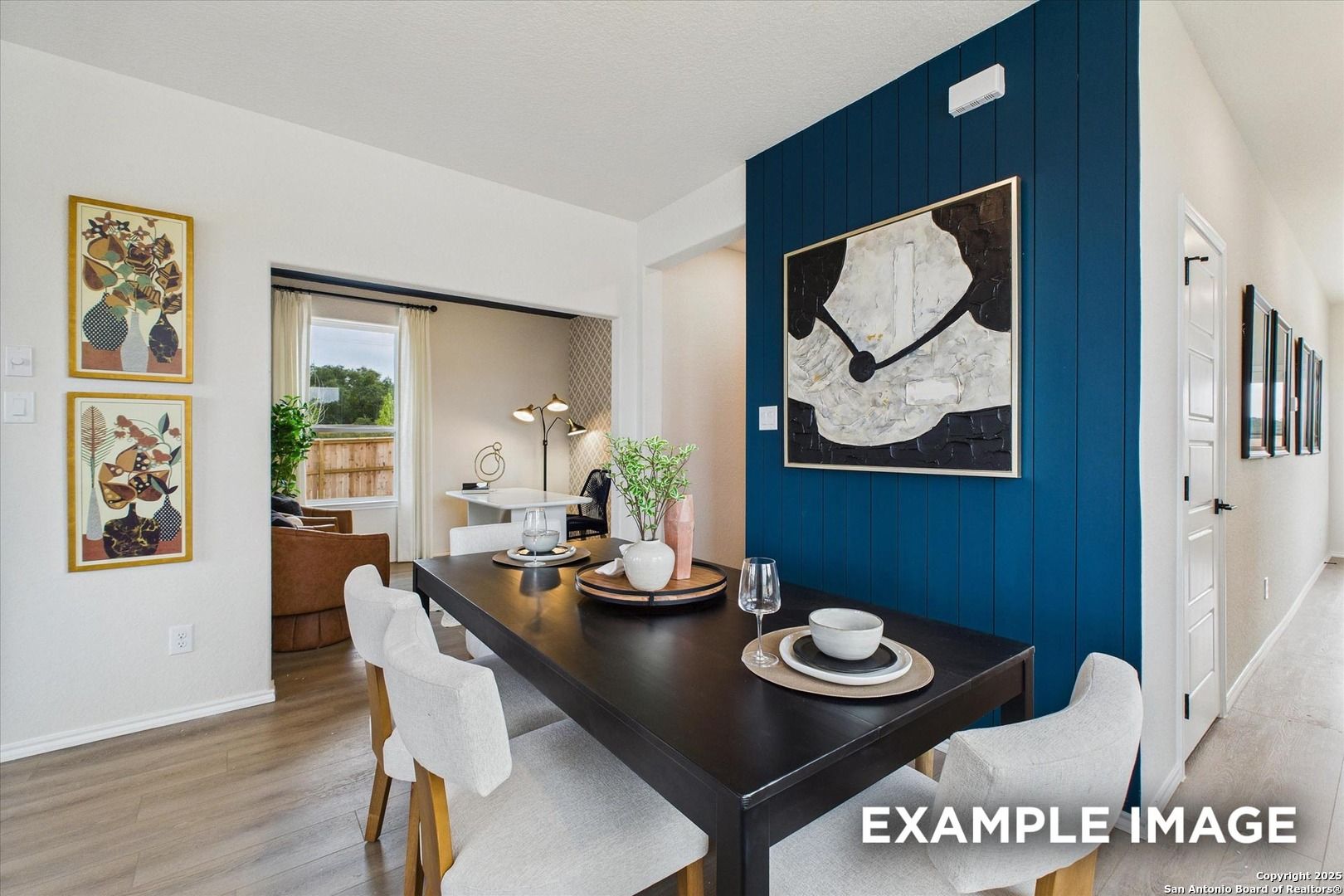 Elegant dining room with navy shiplap wall, abstract art, dark table and white chairs in Davidson Homes The Florence C, San Antonio