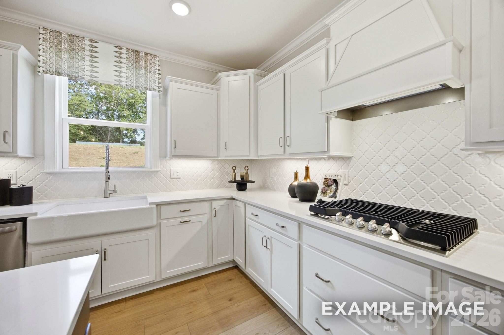 Modern white kitchen with farmhouse sink and gas range in The Hickory B II floor plan by Davidson Homes in Mooresville, NC.