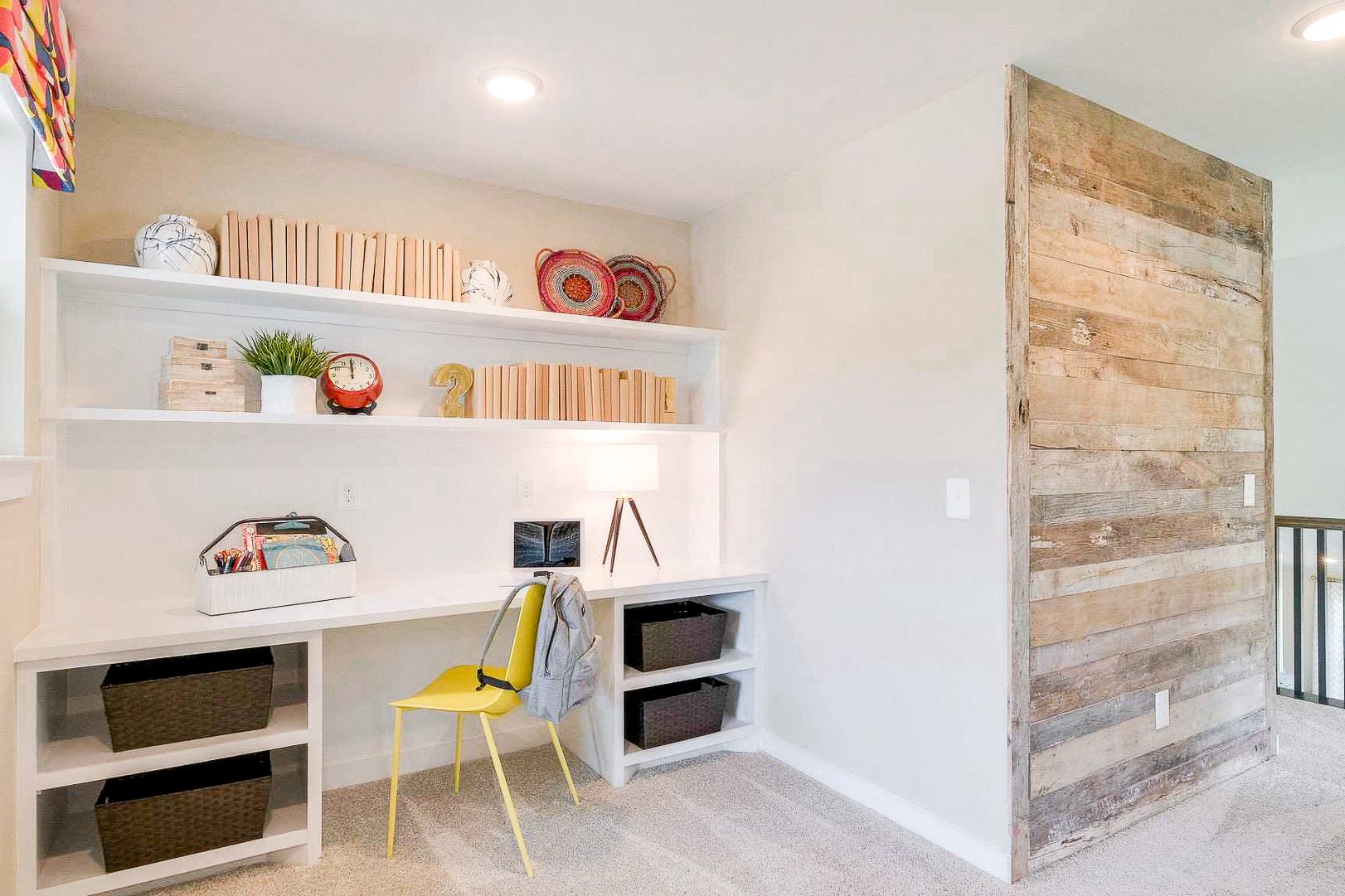 Cozy home office nook at The Meadows in Smyrna TN with built-in shelves, wooden accent wall, desk and yellow chair