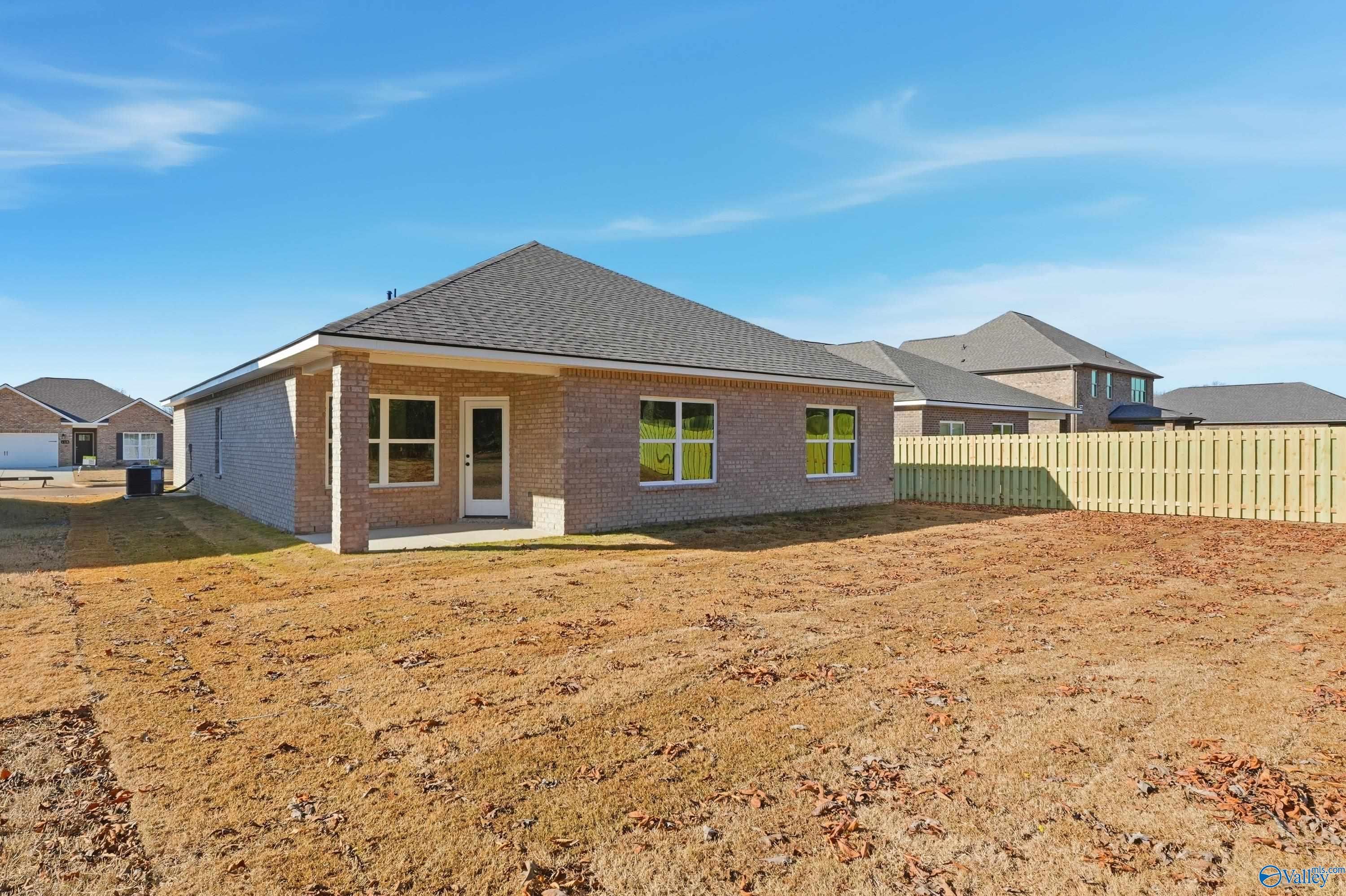 Side view of single-story brick Daphne C home by Davidson Homes in Creek Grove, New Market, Alabama, with covered entry and fenced yard