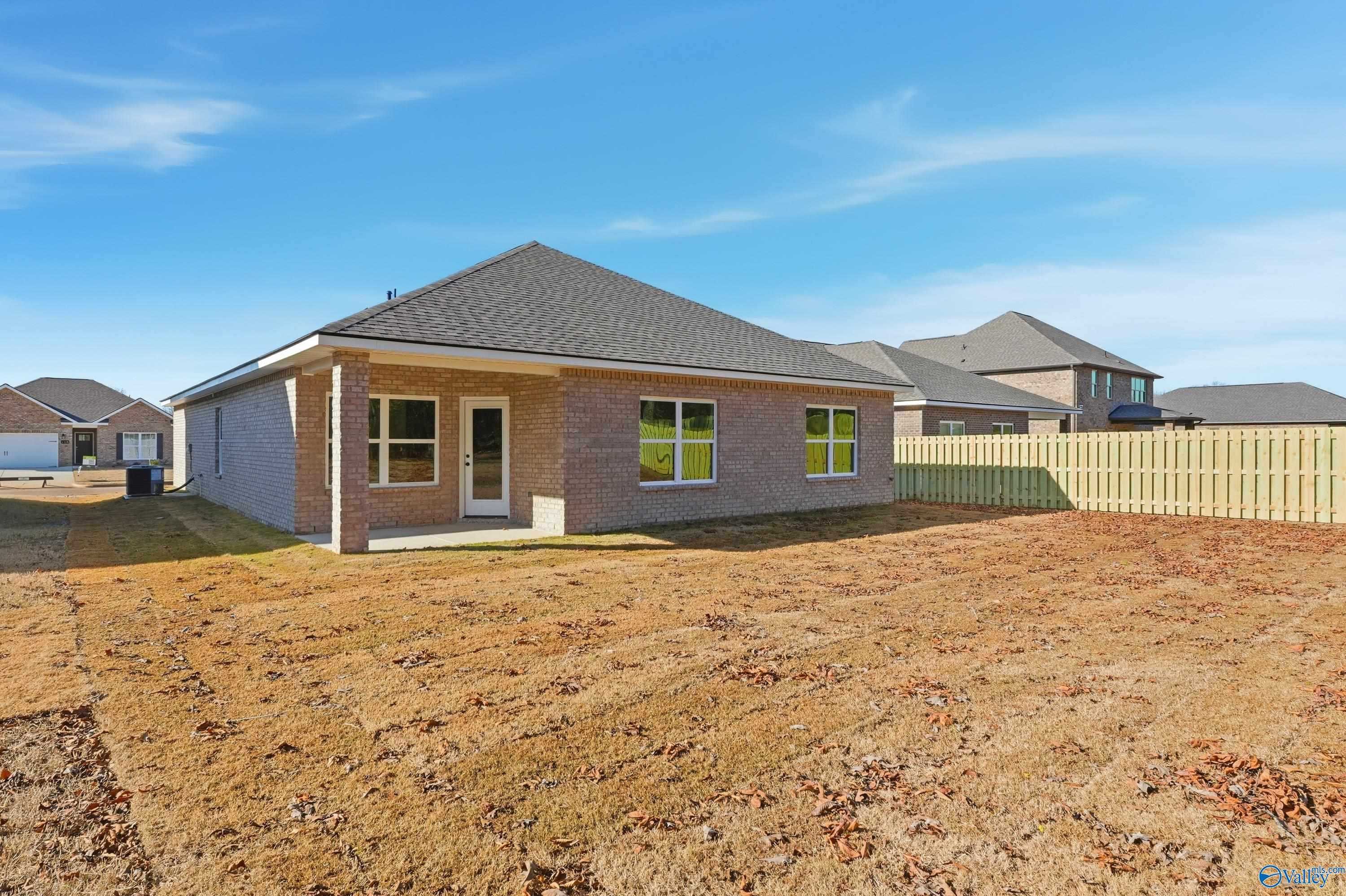 Side view of single-story brick Daphne C home by Davidson Homes in Creek Grove, New Market, Alabama, with covered entry and fenced yard