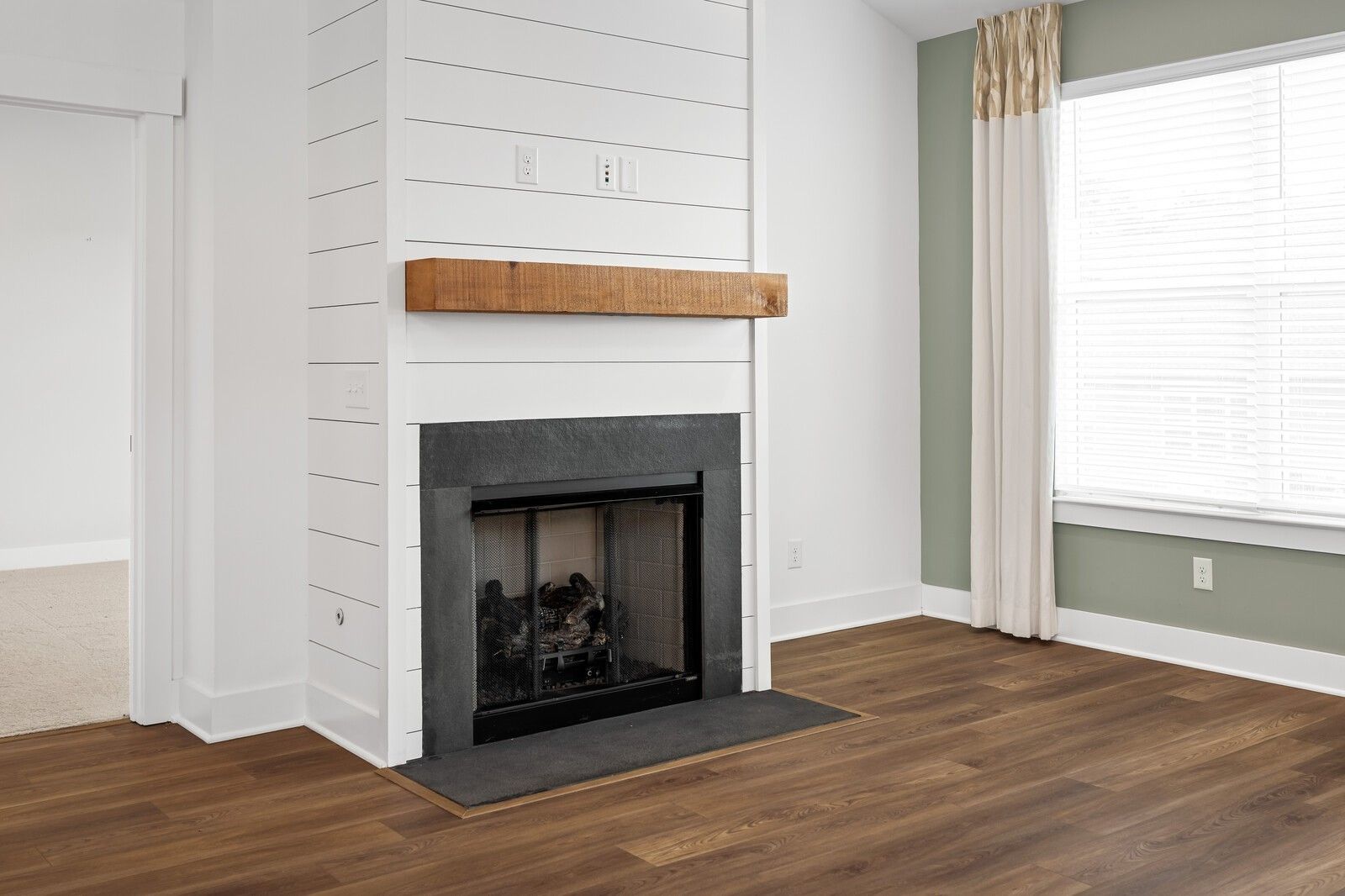 Cozy white shiplap fireplace with wooden mantel and gas logs in living room of Davidson Homes The Ridgeport, Gallatin, Tennessee