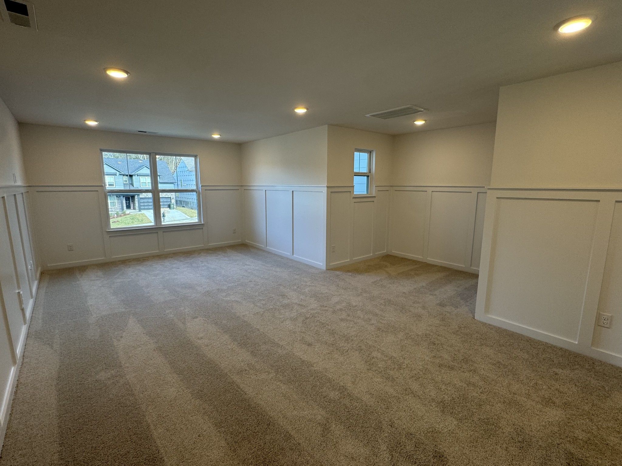 Bright upstairs bedroom with wainscoting, large windows, recessed lights, and carpeted floor in Davidson Homes Ridgeport, Gallatin, TN