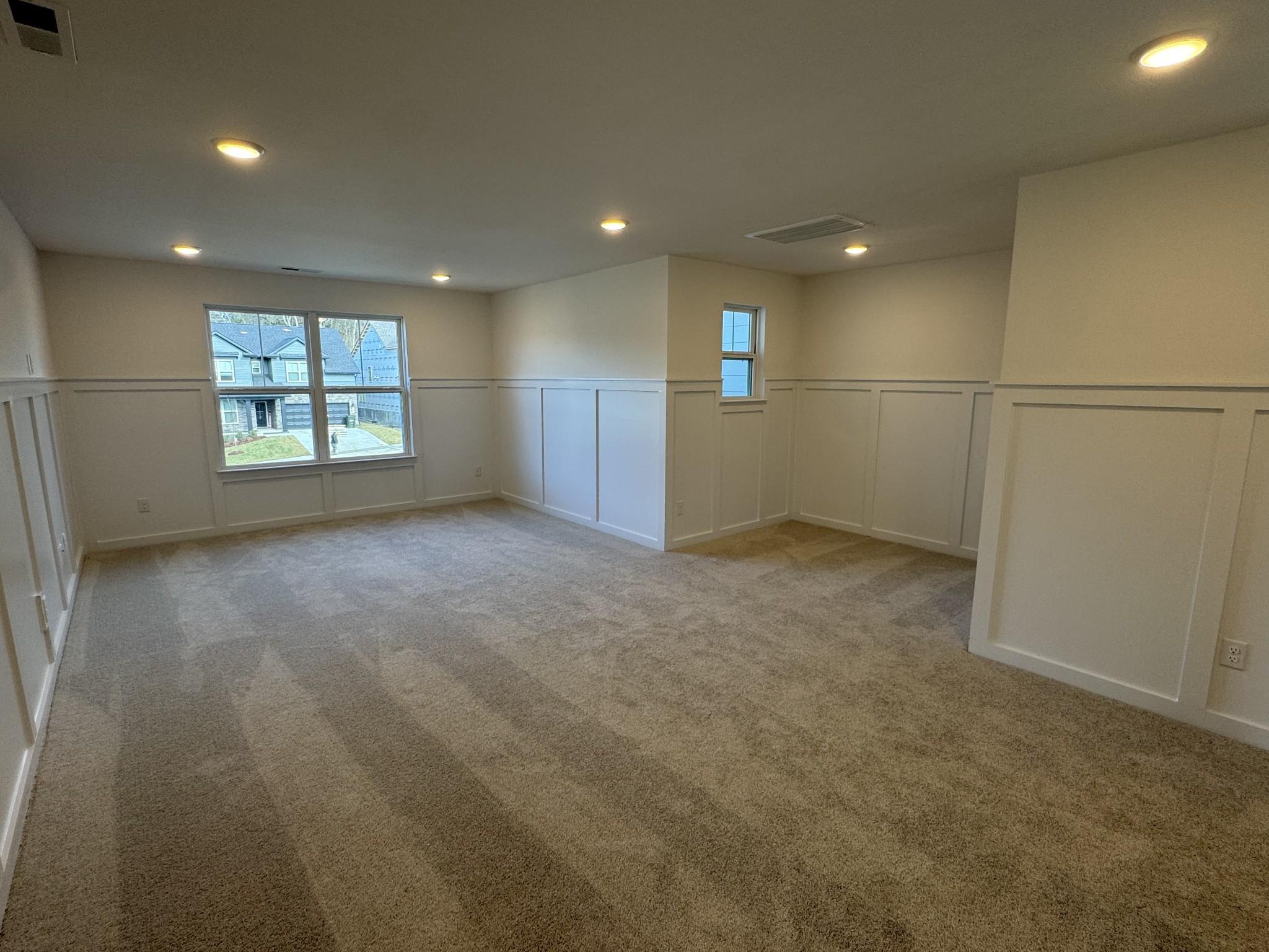 Bright upstairs bedroom with wainscoting, large windows, recessed lights, and carpeted floor in Davidson Homes Ridgeport, Gallatin, TN