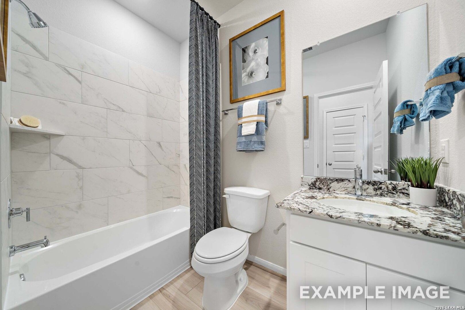 Modern bathroom with marble-look tile tub surround and granite vanity in San Marcos F floor plan, Rayburn Valley, TX.