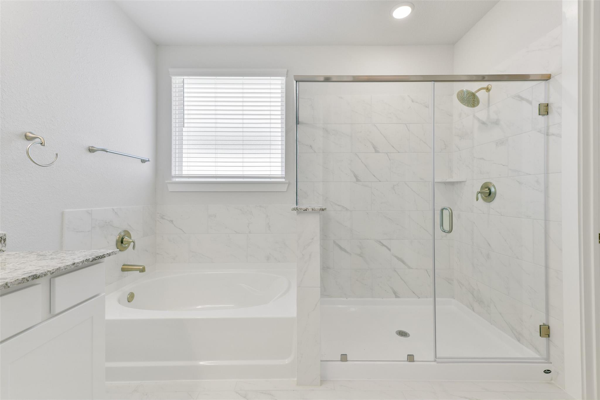 Luxurious master bathroom with freestanding tub, frameless glass shower, and marble double vanity in Davidson Homes The Edward A, Lago Mar