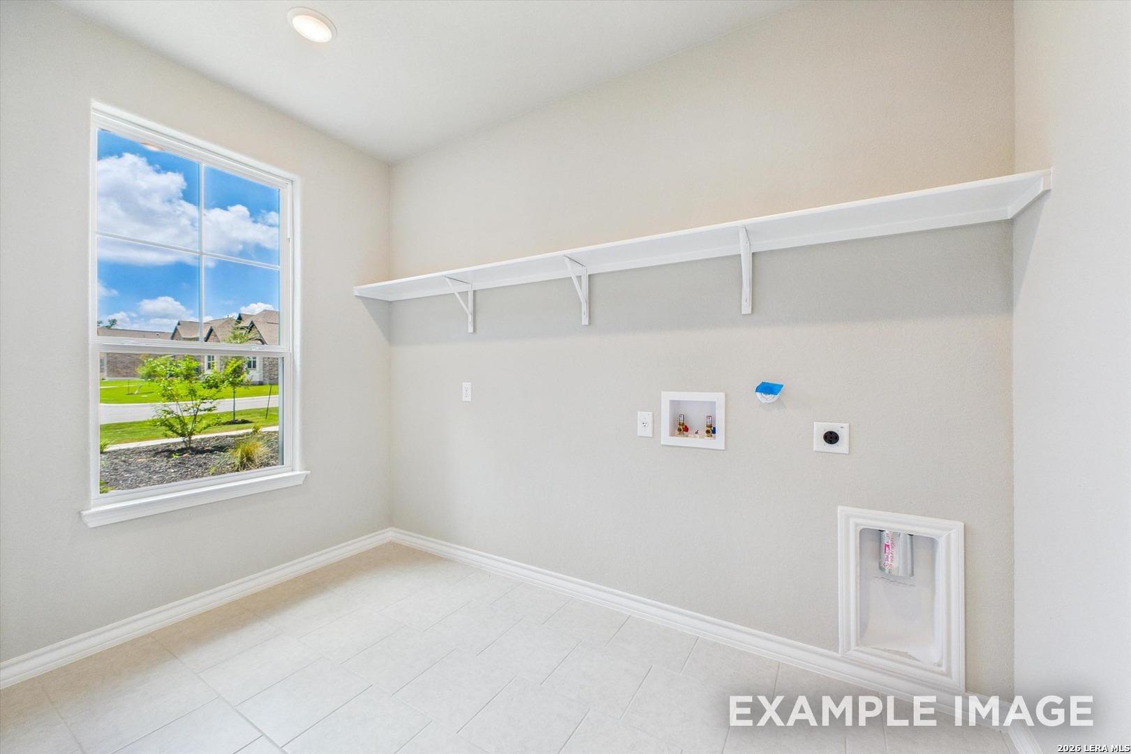 Laundry room with tile flooring and built-in shelving in The Foster F floor plan by Davidson Homes in Potranco Oaks.