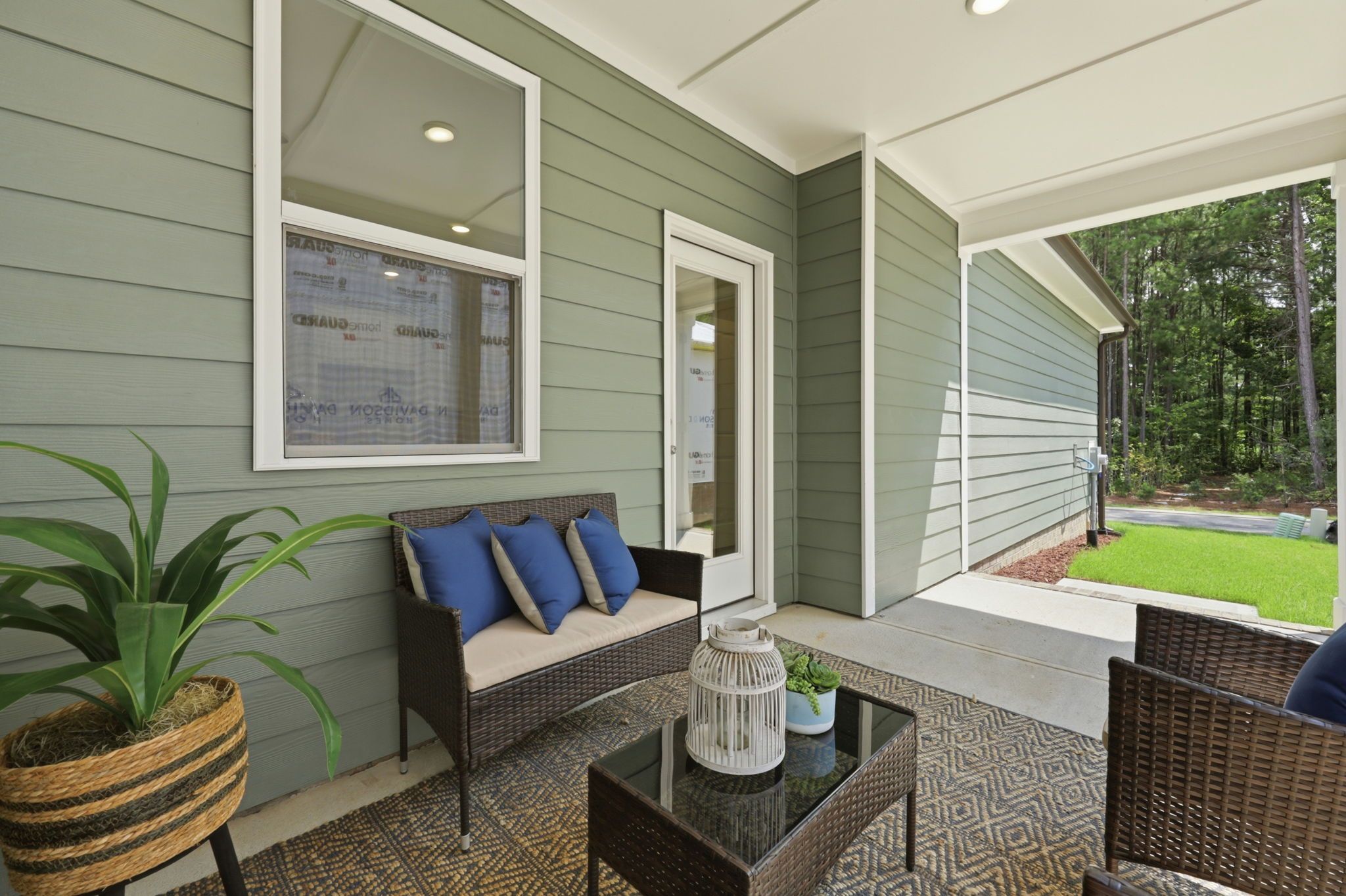Covered patio of The Jordan A floor plan by Davidson Homes featuring sage green siding and outdoor seating area.
