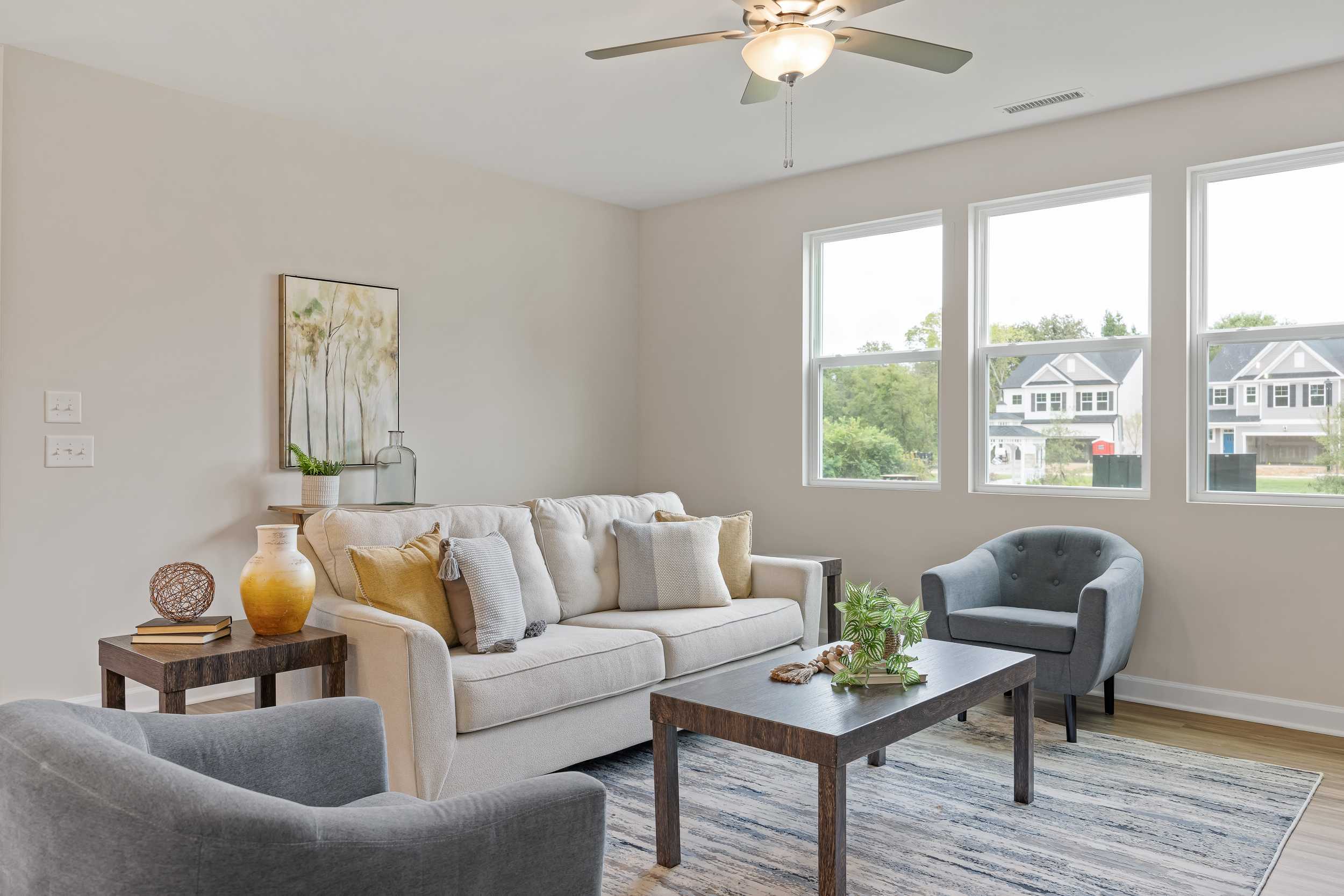 Spacious living room in Gregory Village Lillington NC with beige sofa neutral walls large windows and modern decor by Davidson Homes
