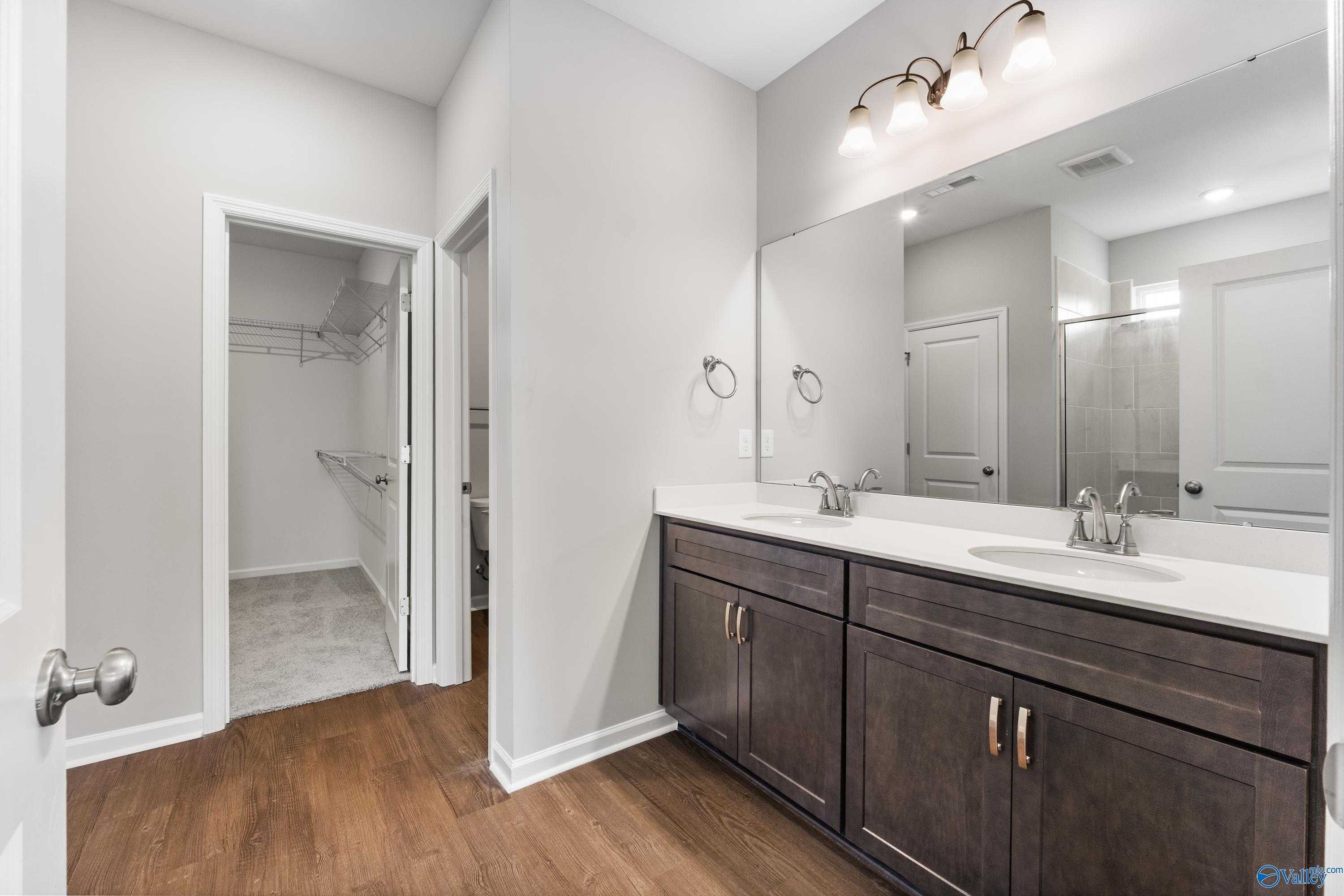Elegant master bathroom featuring double vanity, large mirrors, walk-in closet, and shower in Davidson Homes The Sanctuary, Huntsville