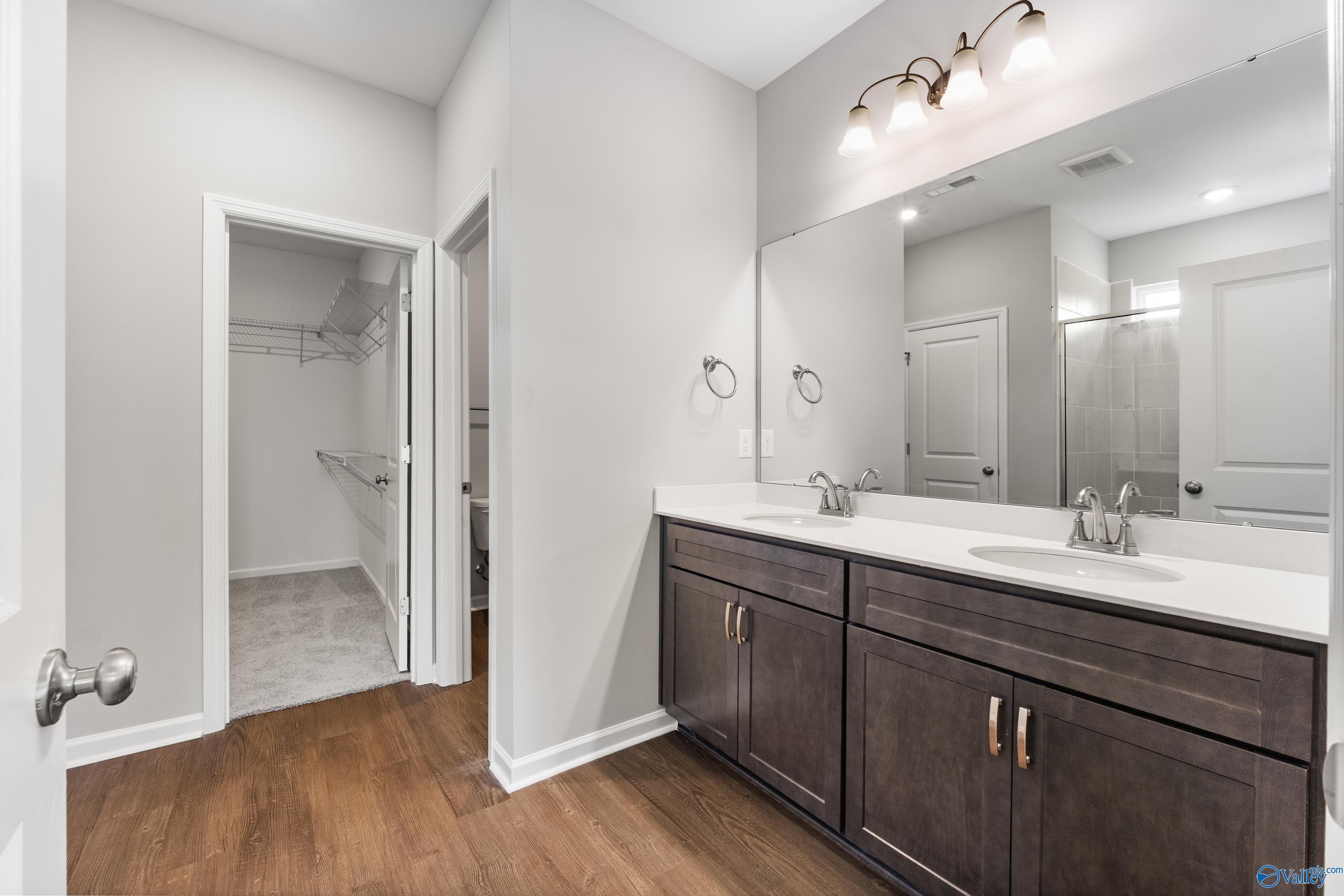 Modern master bathroom with double vanity sinks, large mirrors, and walk-in closet in Davidson Homes The Sanctuary, Huntsville AL
