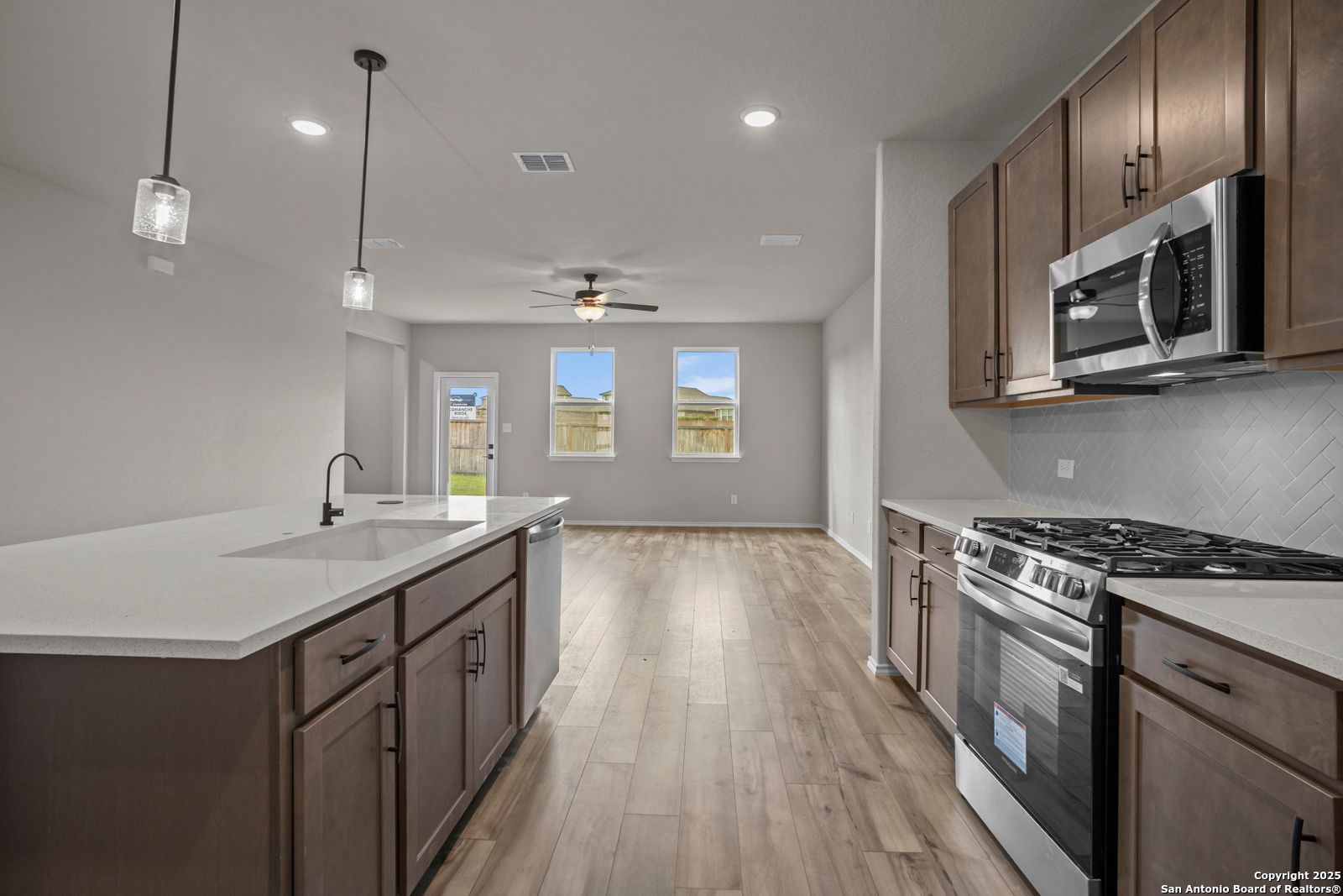 Modern kitchen island with stainless steel appliances and open-concept living in 4-bedroom Davidson Homes The Douglas F, San Antonio