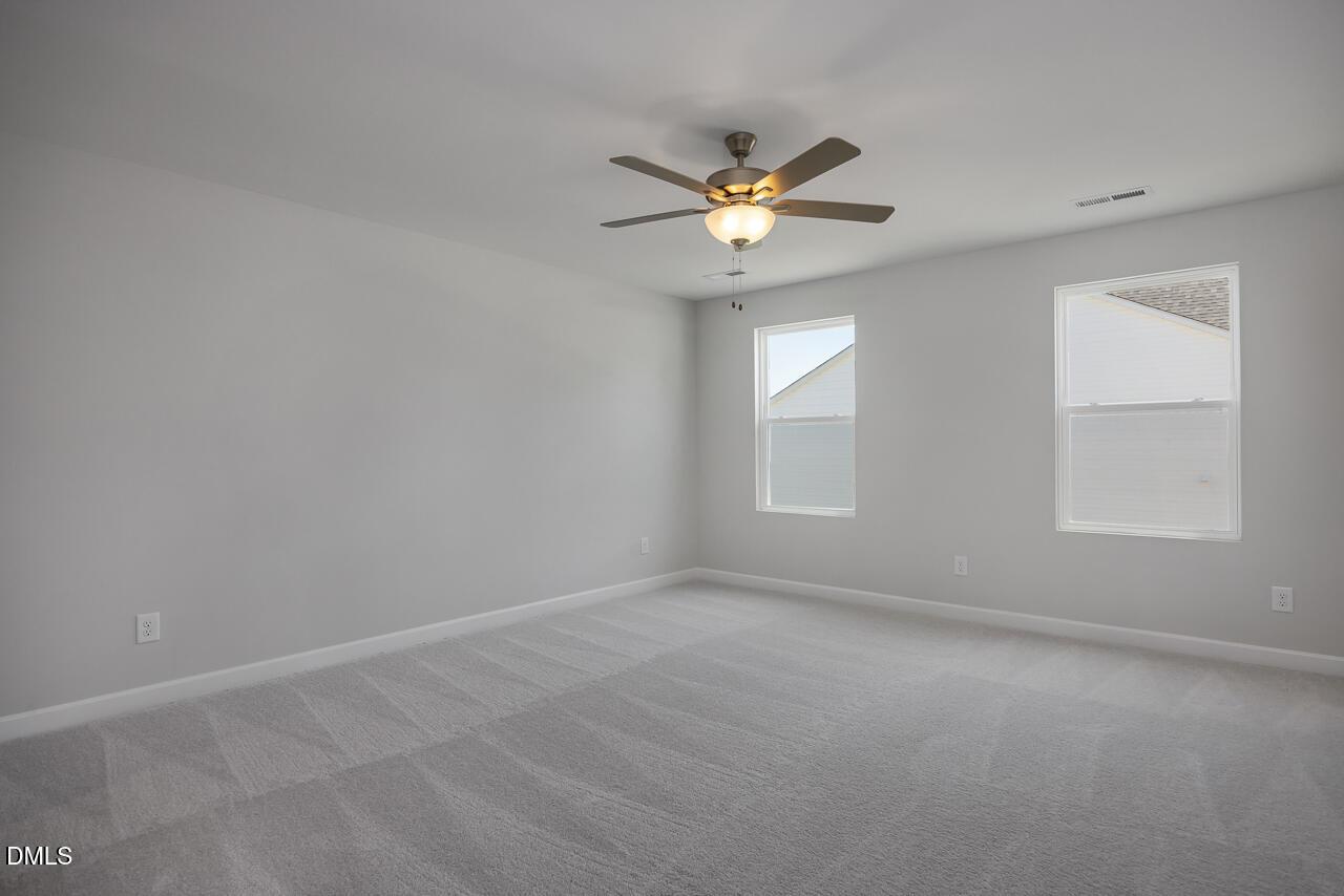 Spacious, neutral-toned bedroom with ceiling fan in The Adalynn B floor plan at Gregory Village, Lillington, NC.