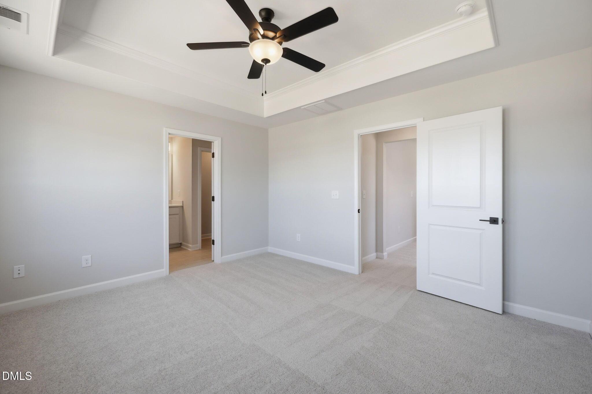 Primary bedroom with tray ceiling and ceiling fan in The Avery floor plan at Forestville Yard Townhomes in Knightdale, NC.