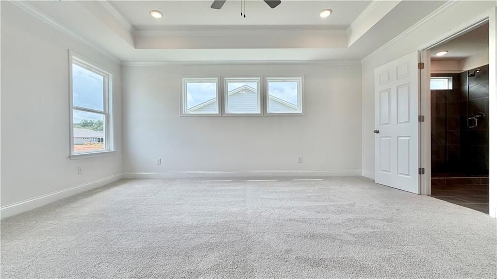 Spacious primary bedroom with tray ceiling in The Hickory C floor plan by Davidson Homes at Wehunt Meadows, Hoschton, GA.