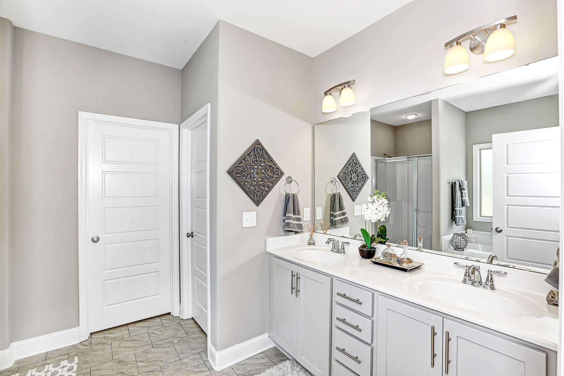 Spacious master bathroom with double vanity, large mirror, orchid accents and walk-in shower at Stone Creek Phase II in Cullman Alabama