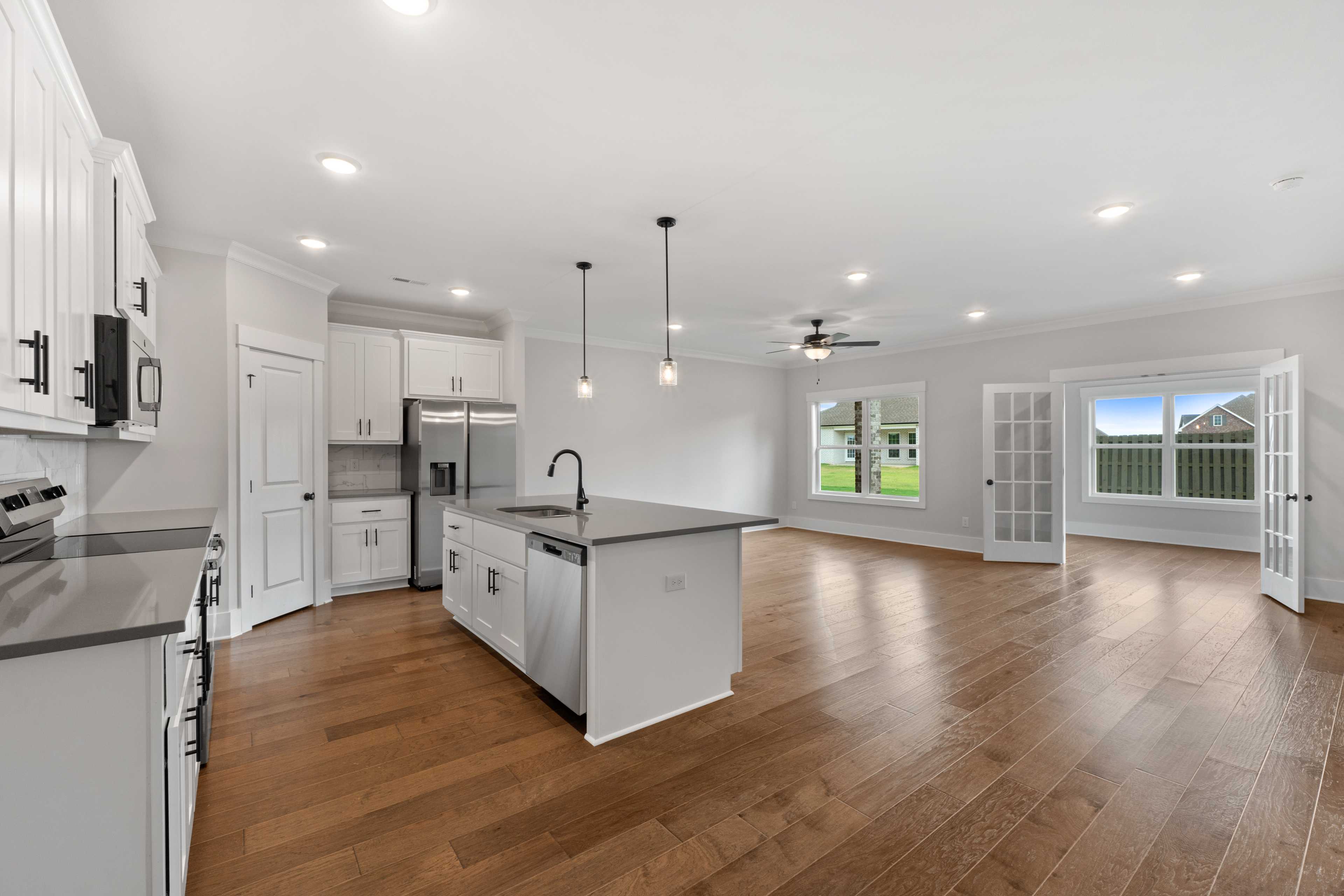 Modern kitchen at The Villas at Barnett's Crossing in Madison AL with white cabinets, quartz island, stainless appliances, hardwood floors