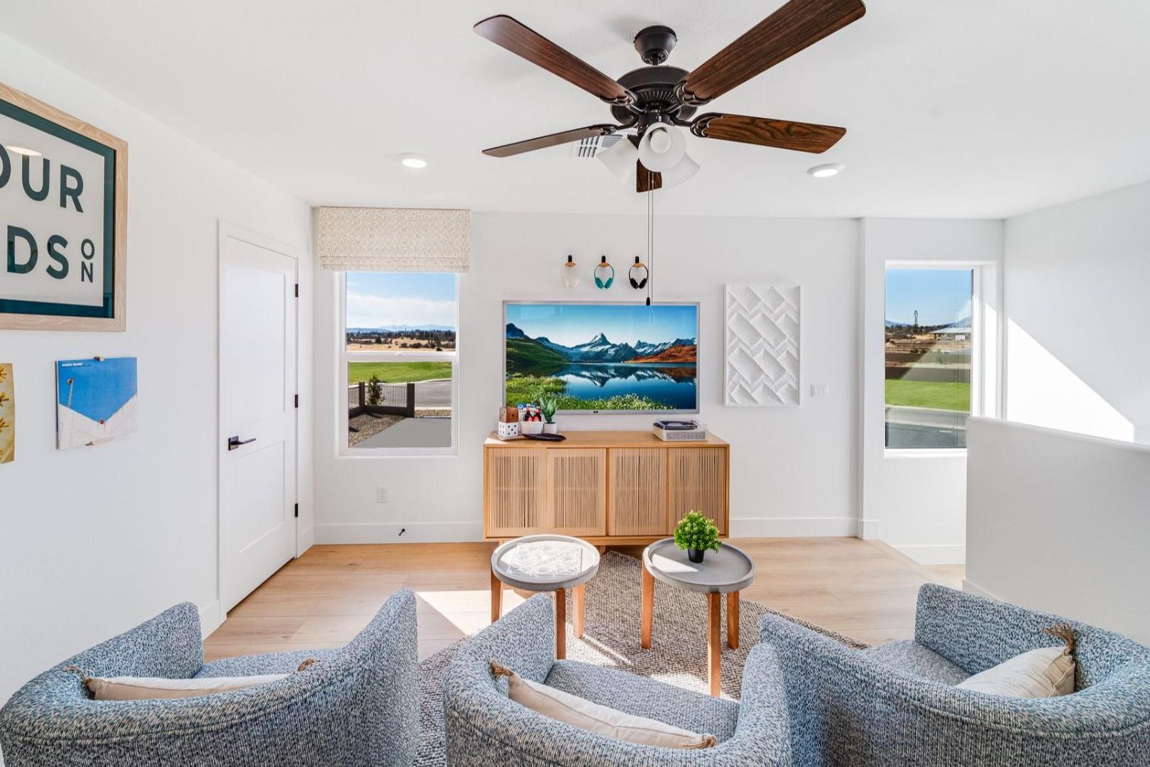 Cozy loft seating area in South Ranch Southern Collection Prescott AZ home with gray armchairs wooden floors ceiling fan and scenic views