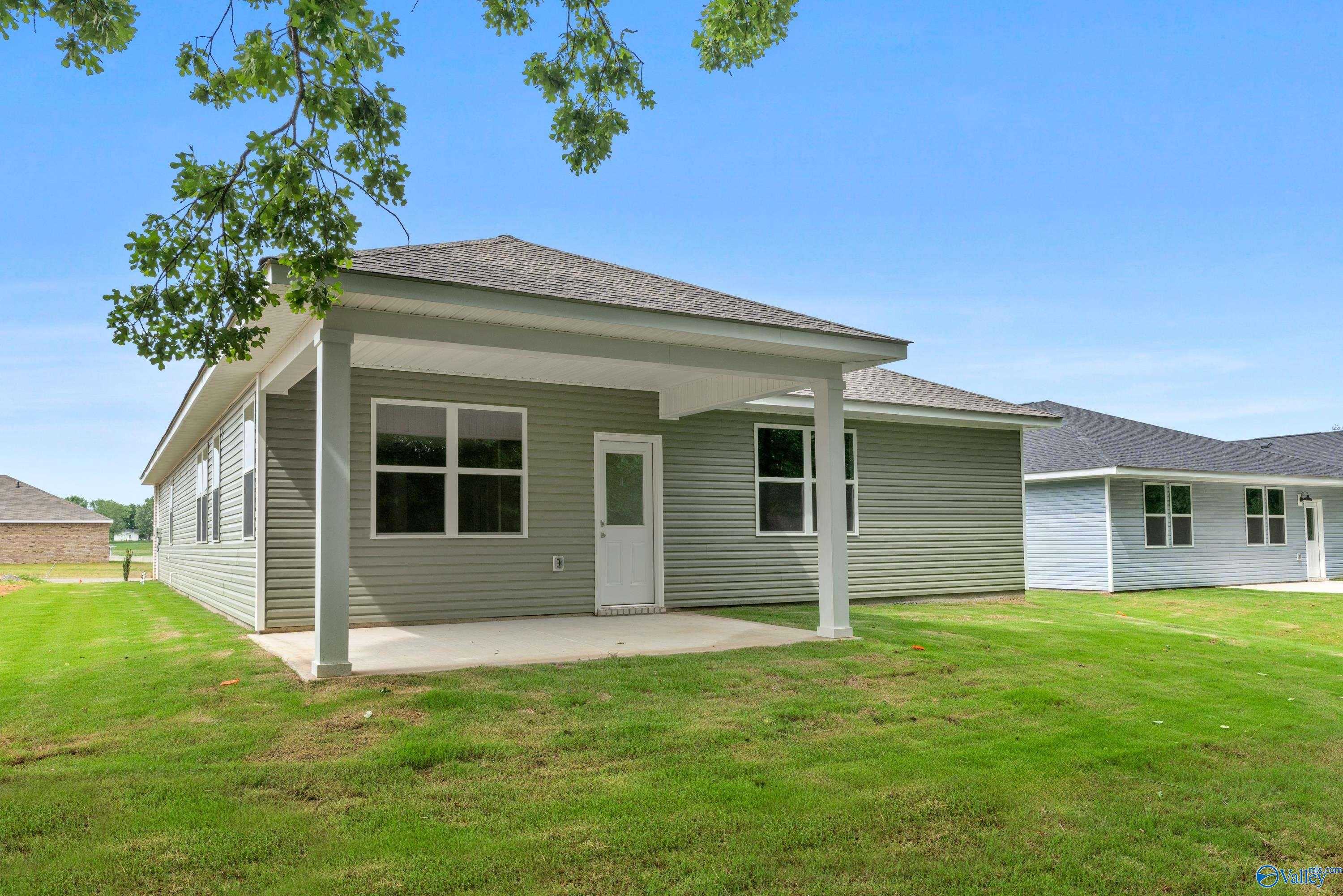 Gray single-story home with covered side patio, large windows, glass door, and lush green lawn in Bailey Park, Fayetteville, Tennessee