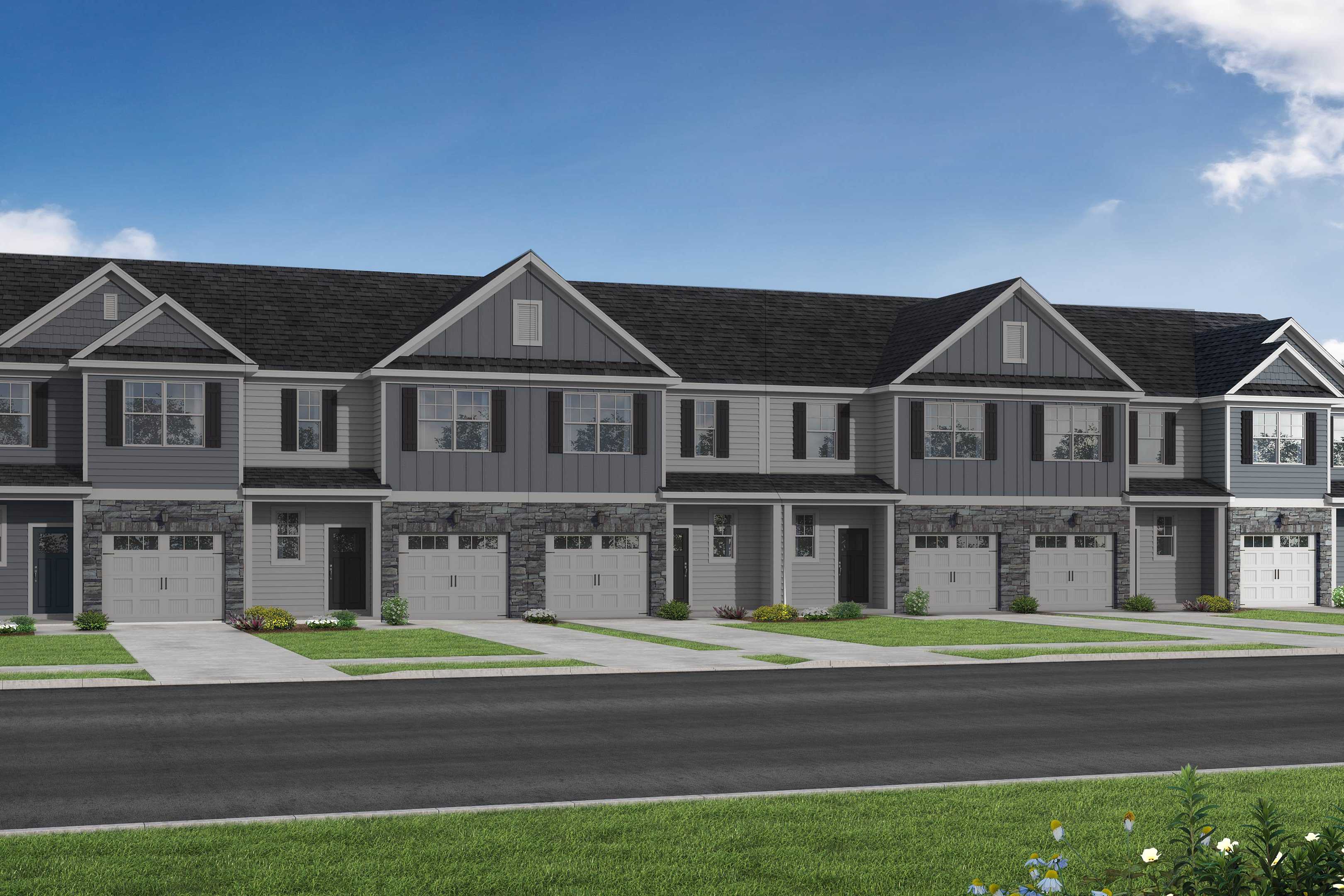 Modern row of The Graham townhomes with gray siding, dark gabled roofs, garages, and front porches in Fuquay-Varina