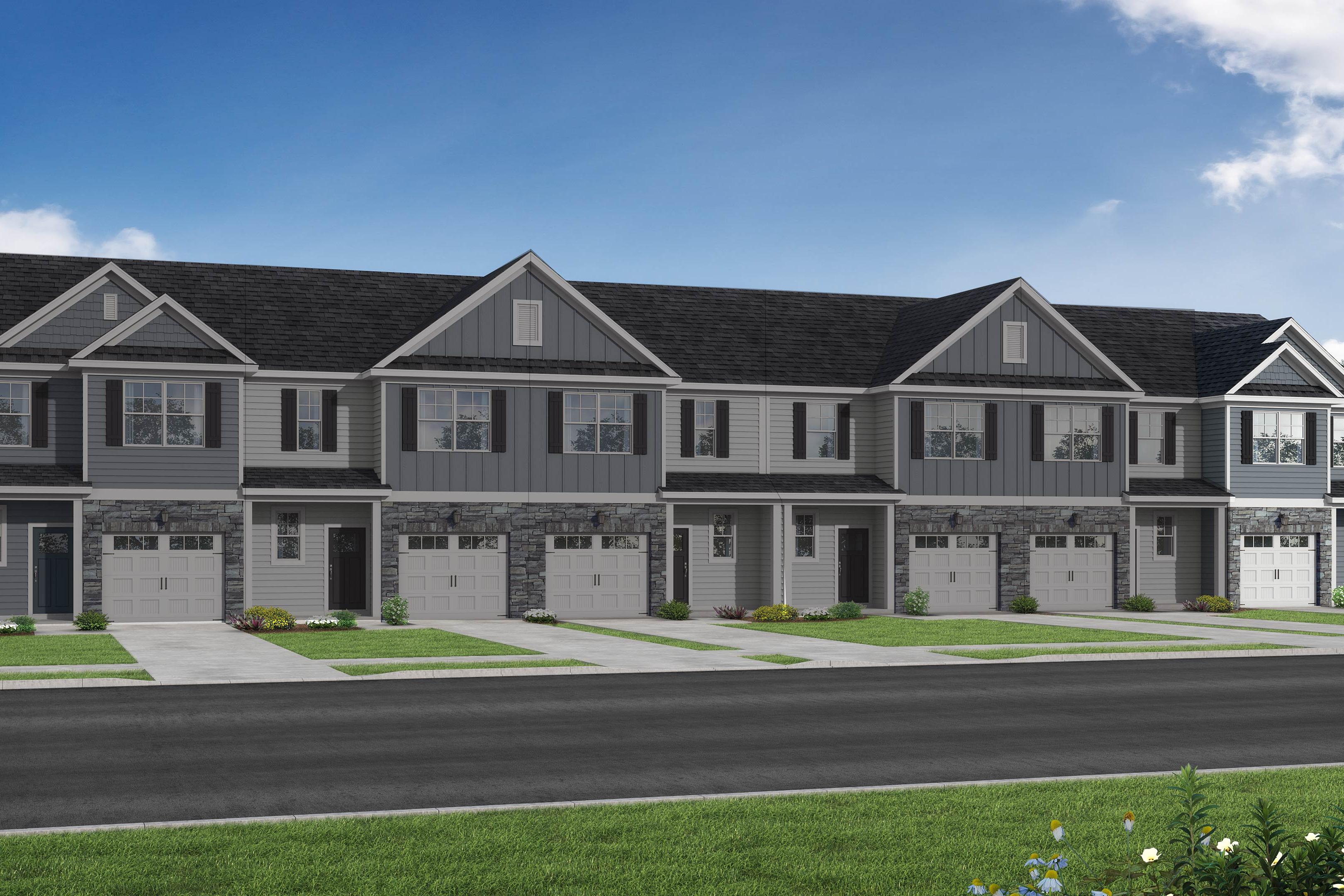 Modern row of The Graham townhomes with gray siding, dark gabled roofs, garages, and front porches in Fuquay-Varina