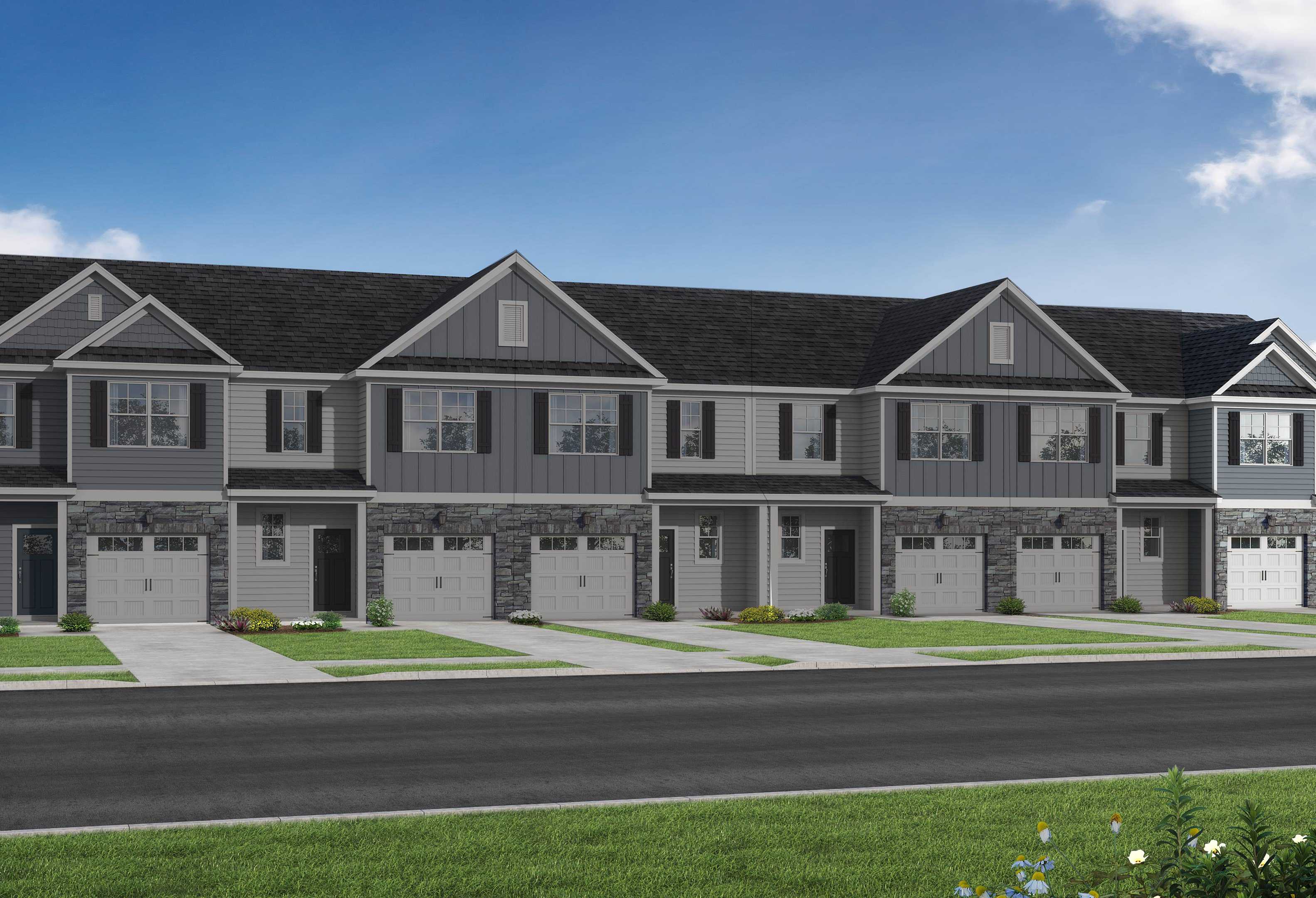 Modern row of The Graham townhomes with gray siding, dark gabled roofs, garages, and front porches in Fuquay-Varina