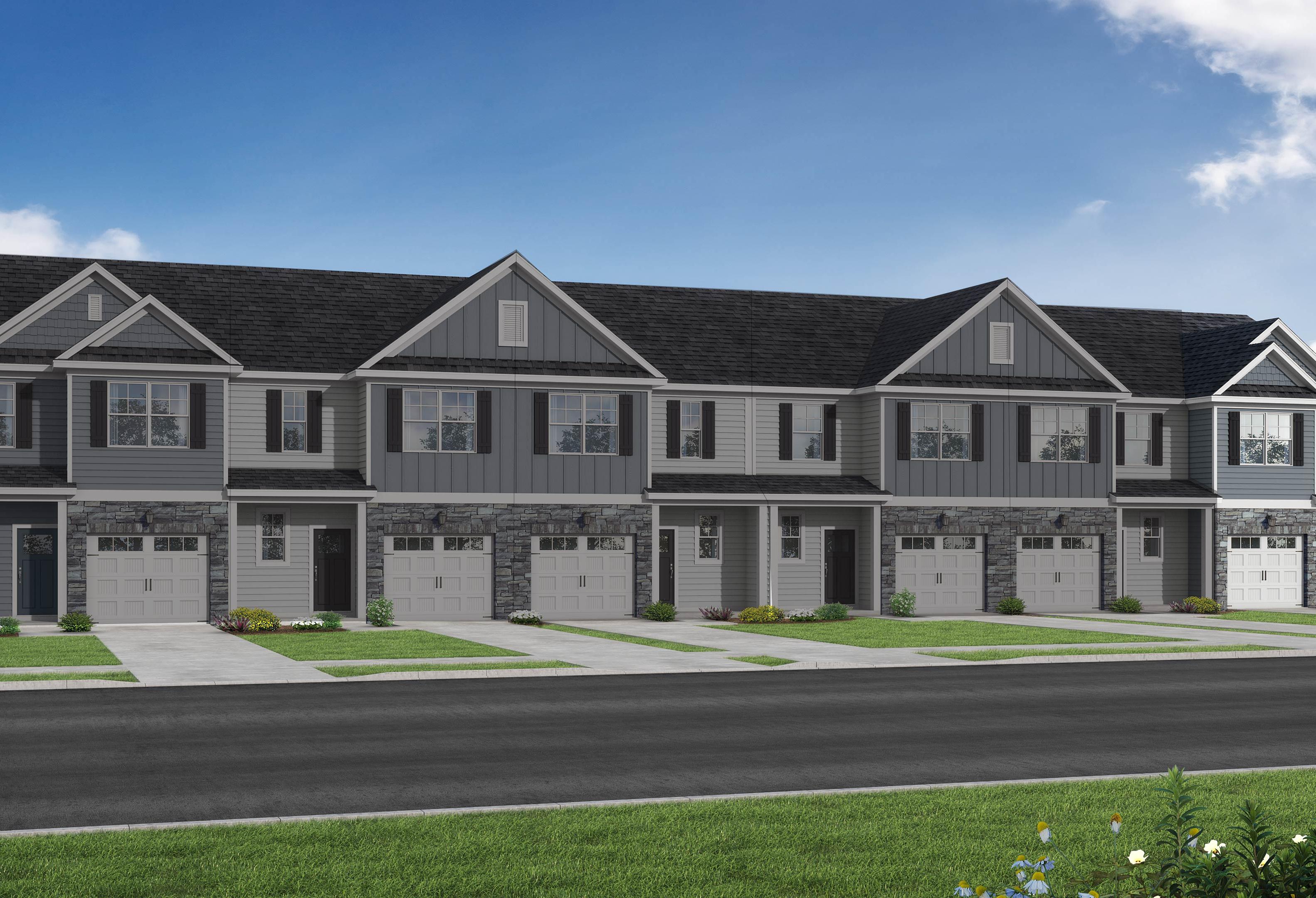 Modern row of The Graham townhomes with gray siding, dark gabled roofs, garages, and front porches in Fuquay-Varina