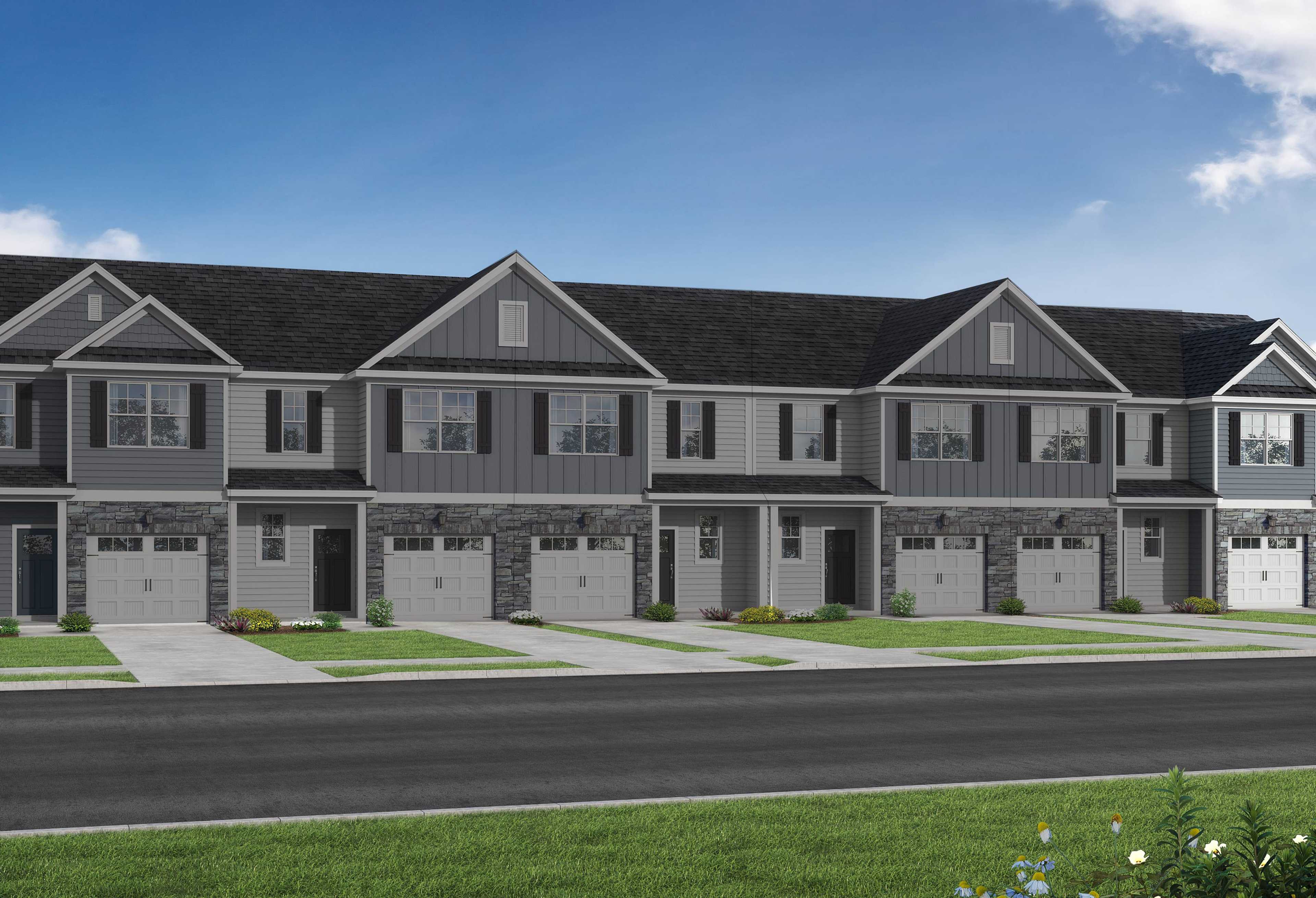 Modern row of The Graham townhomes with gray siding, dark gabled roofs, garages, and front porches in Fuquay-Varina