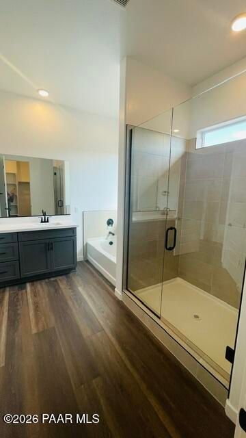 Modern primary bathroom with glass walk-in shower, soaking tub, and dark vanity in The Aurea C home at Hidden Hills, Prescott