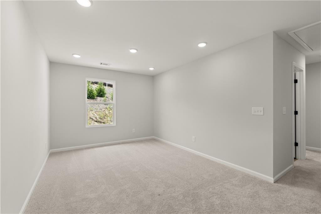 Spacious bedroom with neutral carpet and recessed lighting in The Hartwell A floor plan at The Bluffs, Canton, Georgia.