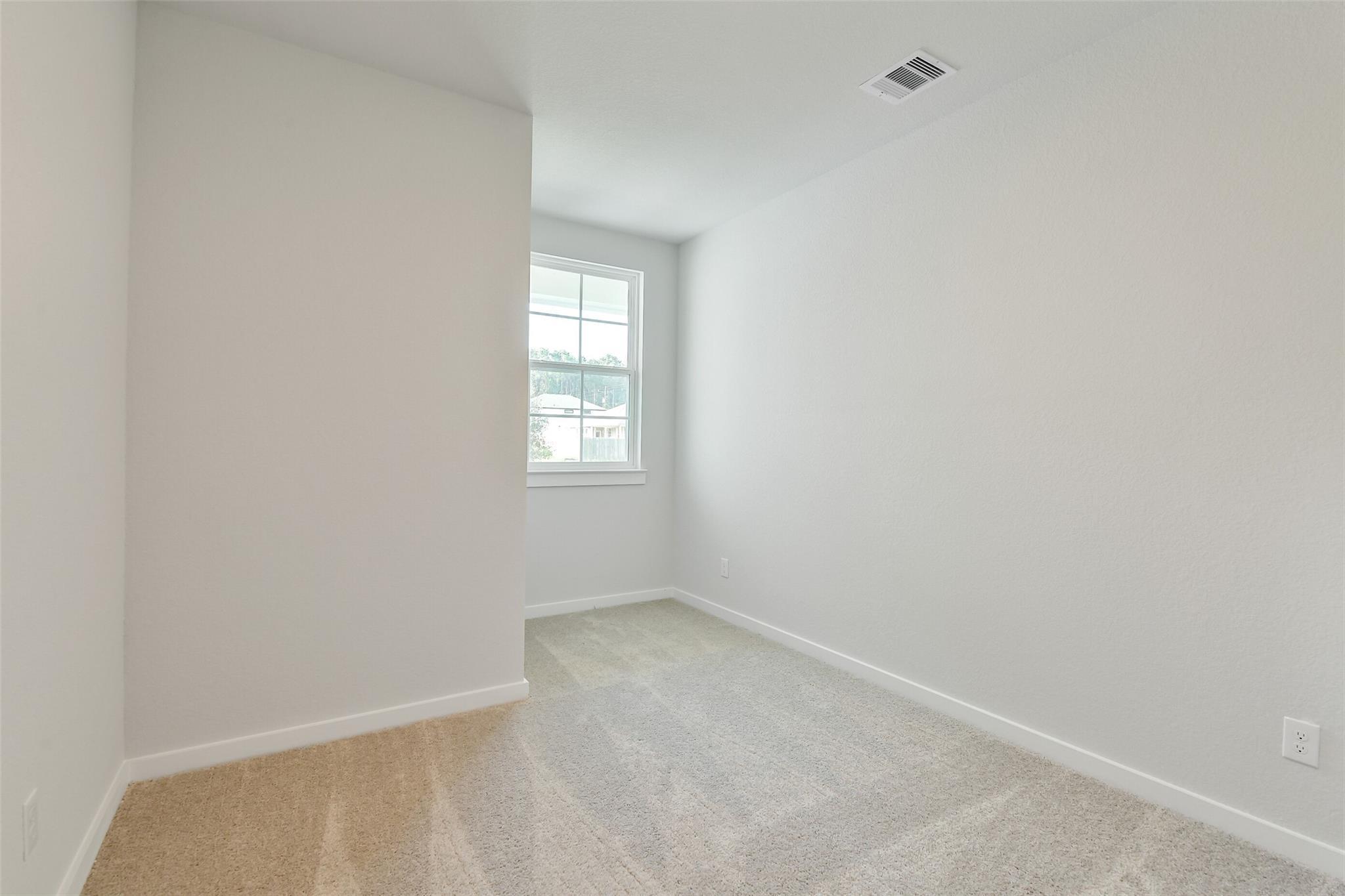 Bright secondary bedroom with window, neutral walls and carpet in Davidson Homes The Colorado F, Cleveland, Texas