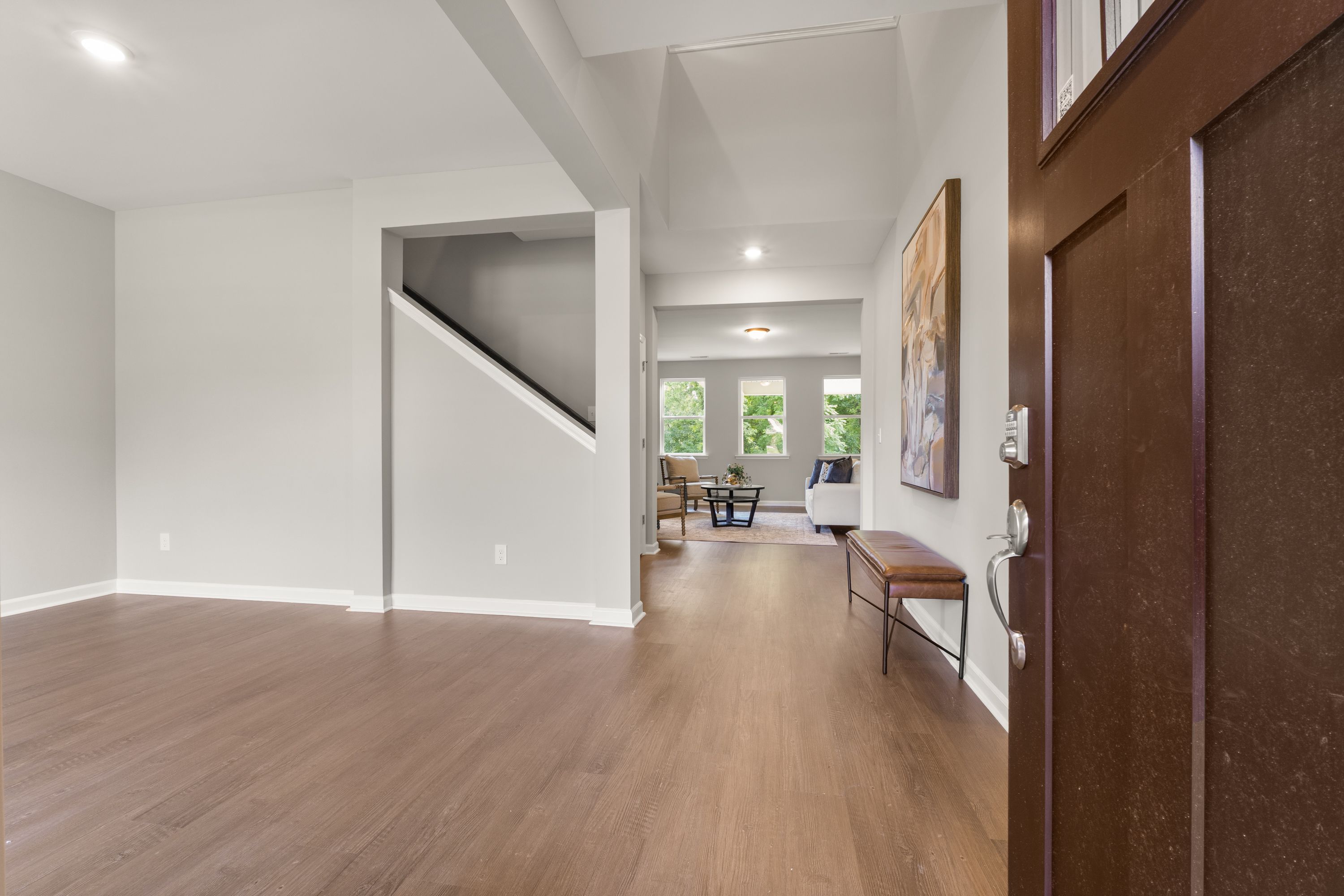 Spacious Avalon E entryway with open staircase, hardwood floors, neutral walls, and large windows overlooking greenery