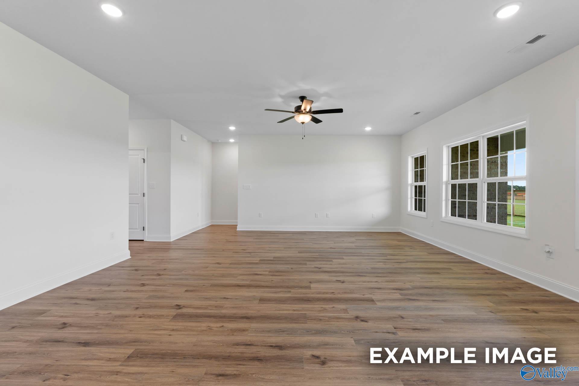 Spacious open-concept living area with wood-style flooring in The Rockford B floor plan at Briercreek, Meridianville, AL.