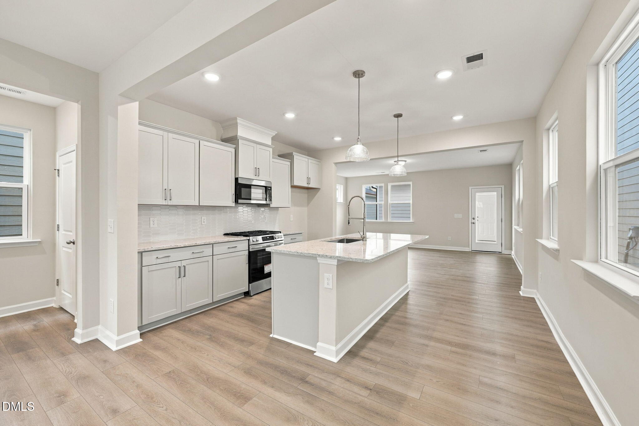 Bright open-concept kitchen with white cabinetry, island, and stainless appliances in Davidson Homes' The Alexander B, Knightdale NC
