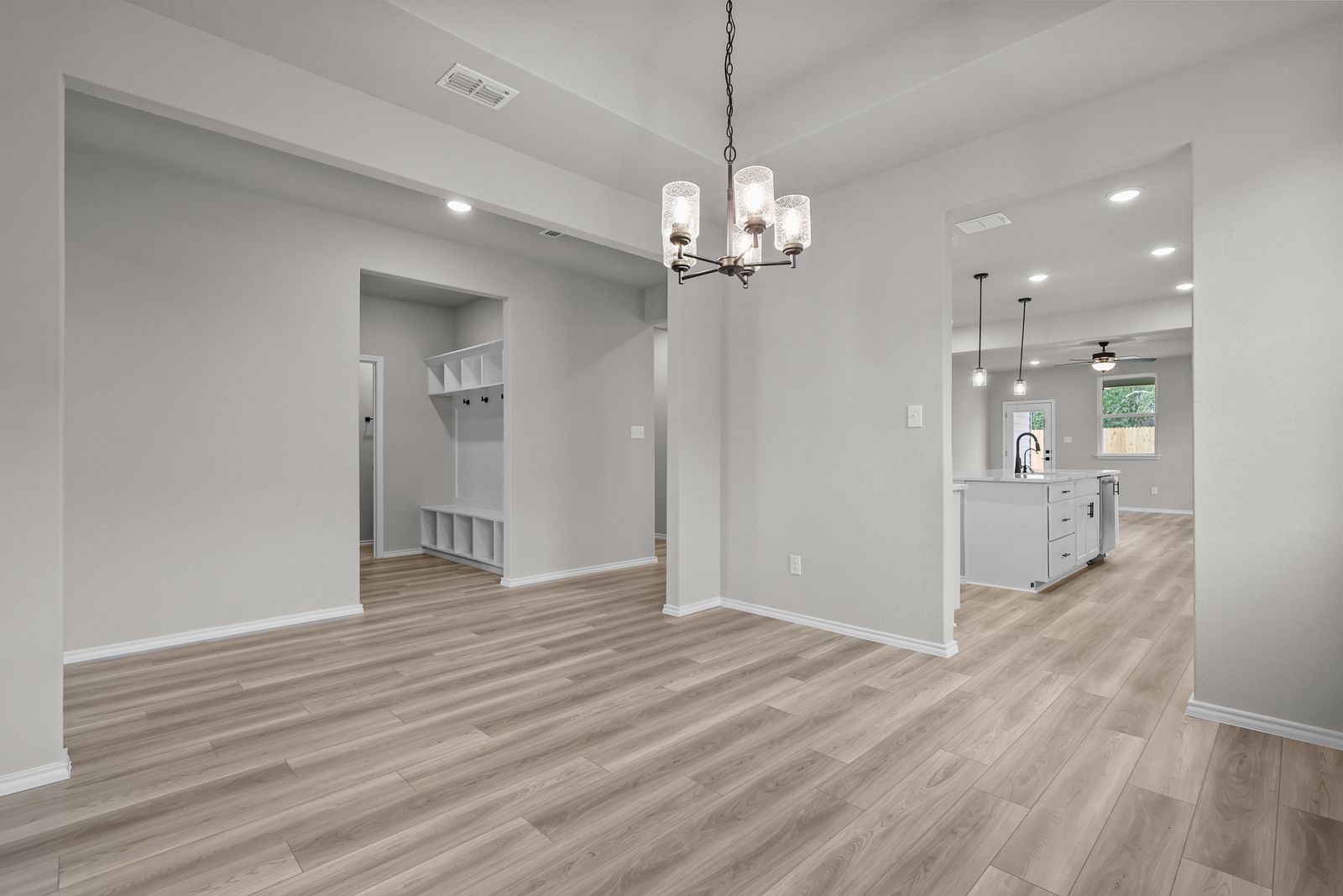 Open-concept dining area in The Glenwood E featuring a mudroom, modern chandelier, and view into the kitchen.