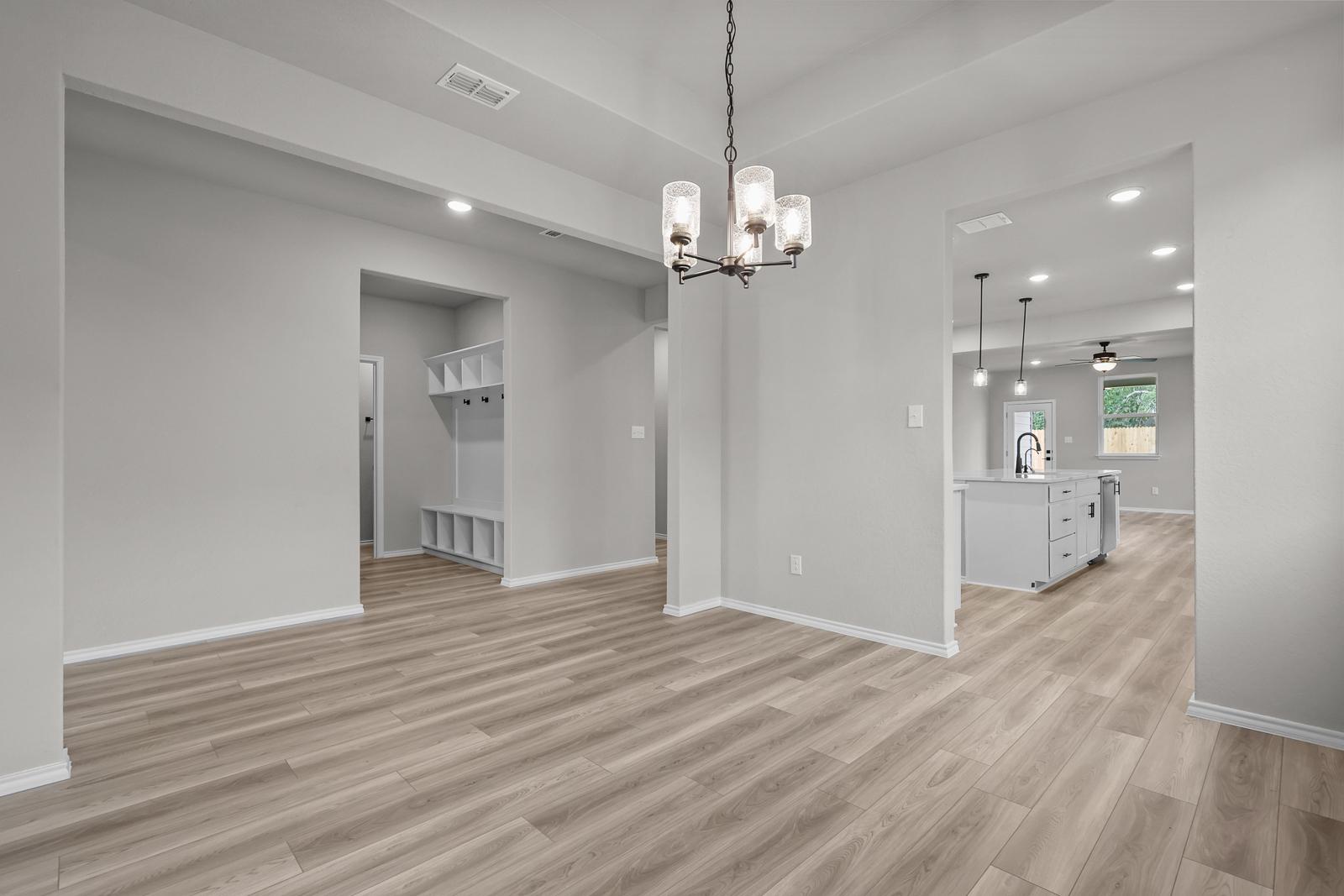 Open-concept dining area in The Glenwood E featuring a mudroom, modern chandelier, and view into the kitchen.